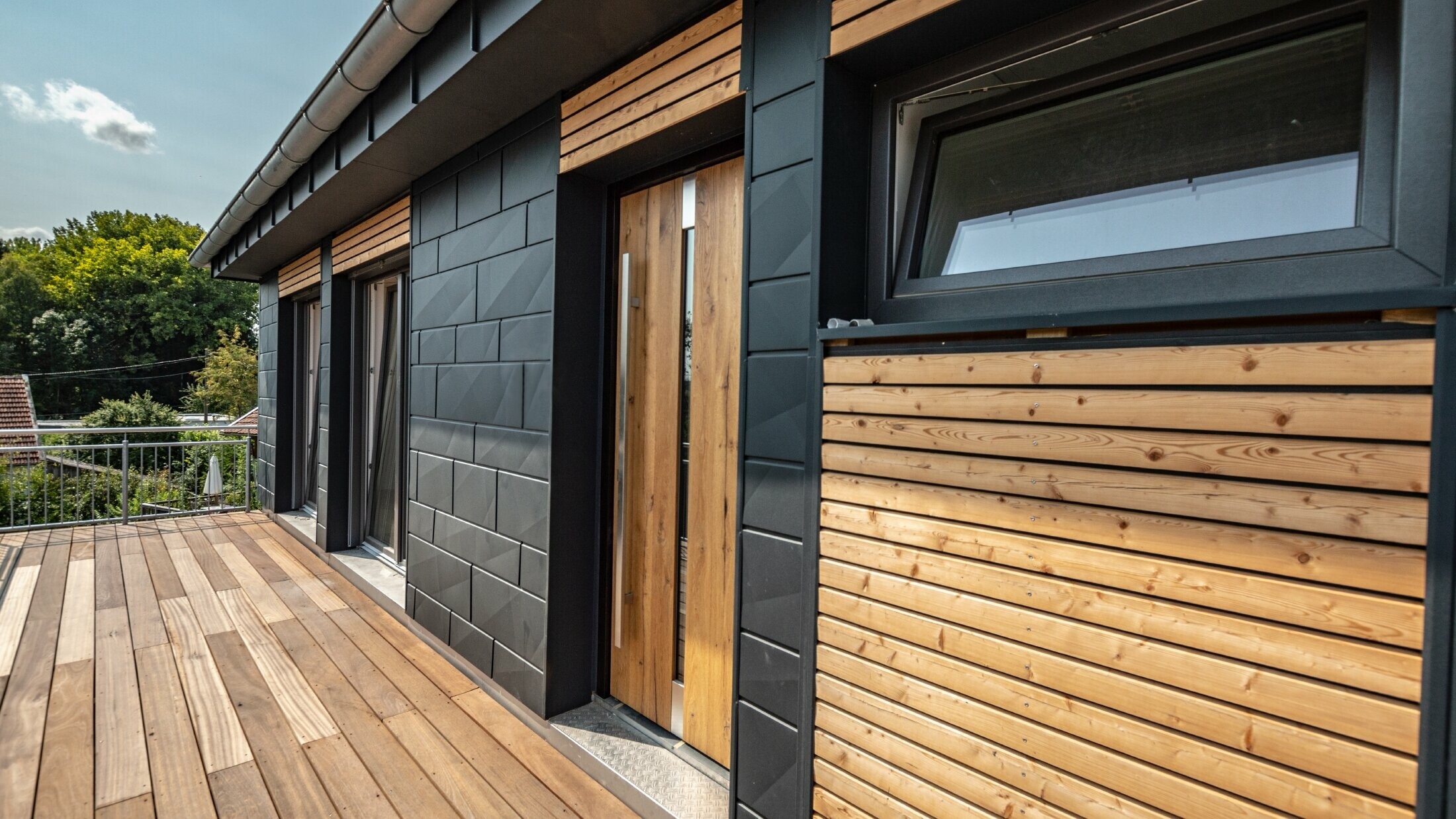 Conception de façade par mélange des matériaux que sont l’aluminium avec le Siding.X PREFA couleur anthracite, et les tasseaux en bois horizontaux.