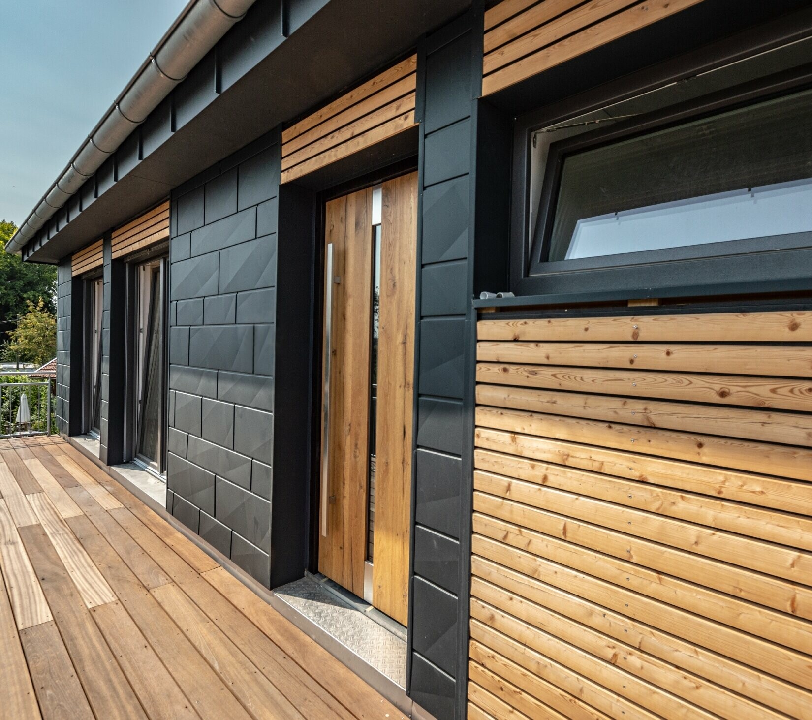 Conception de façade par mélange des matériaux que sont l’aluminium avec le Siding.X PREFA couleur anthracite, et les tasseaux en bois horizontaux.
