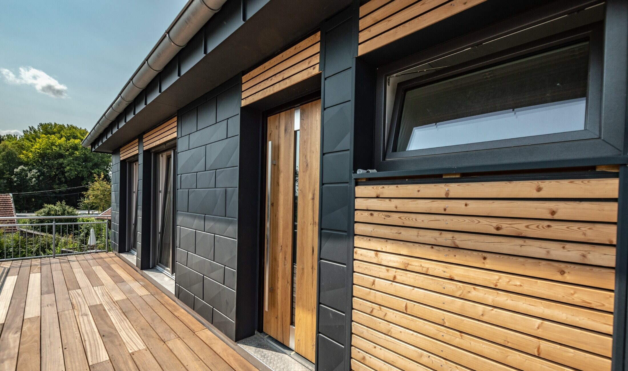 Conception de façade par mélange des matériaux que sont l’aluminium avec le Siding.X PREFA couleur anthracite, et les tasseaux en bois horizontaux.
