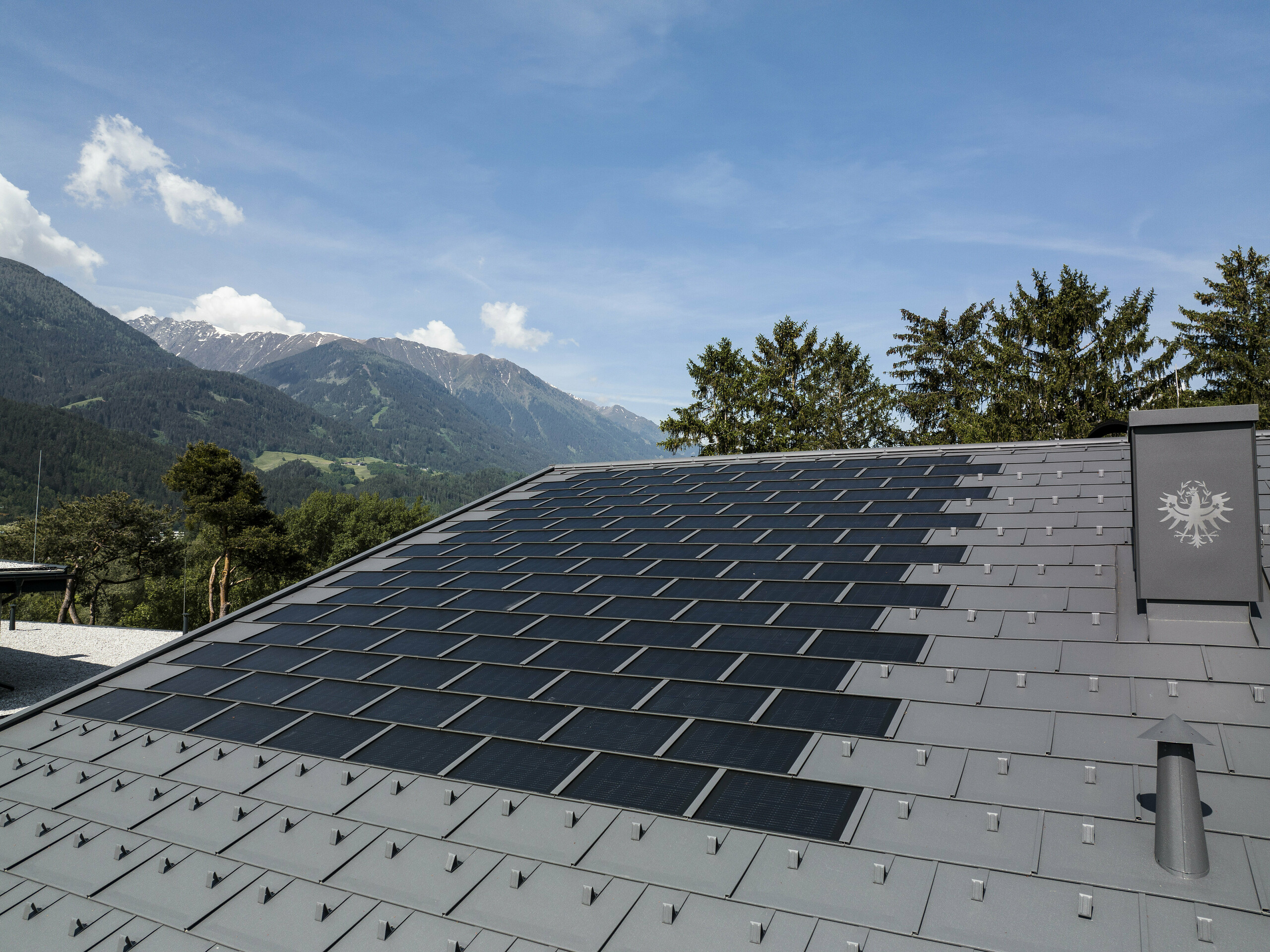 Photo de la toiture au Tyrol, recouverte avec la tuile solaire R.16 de PREFA couleur P.10 gris sombre