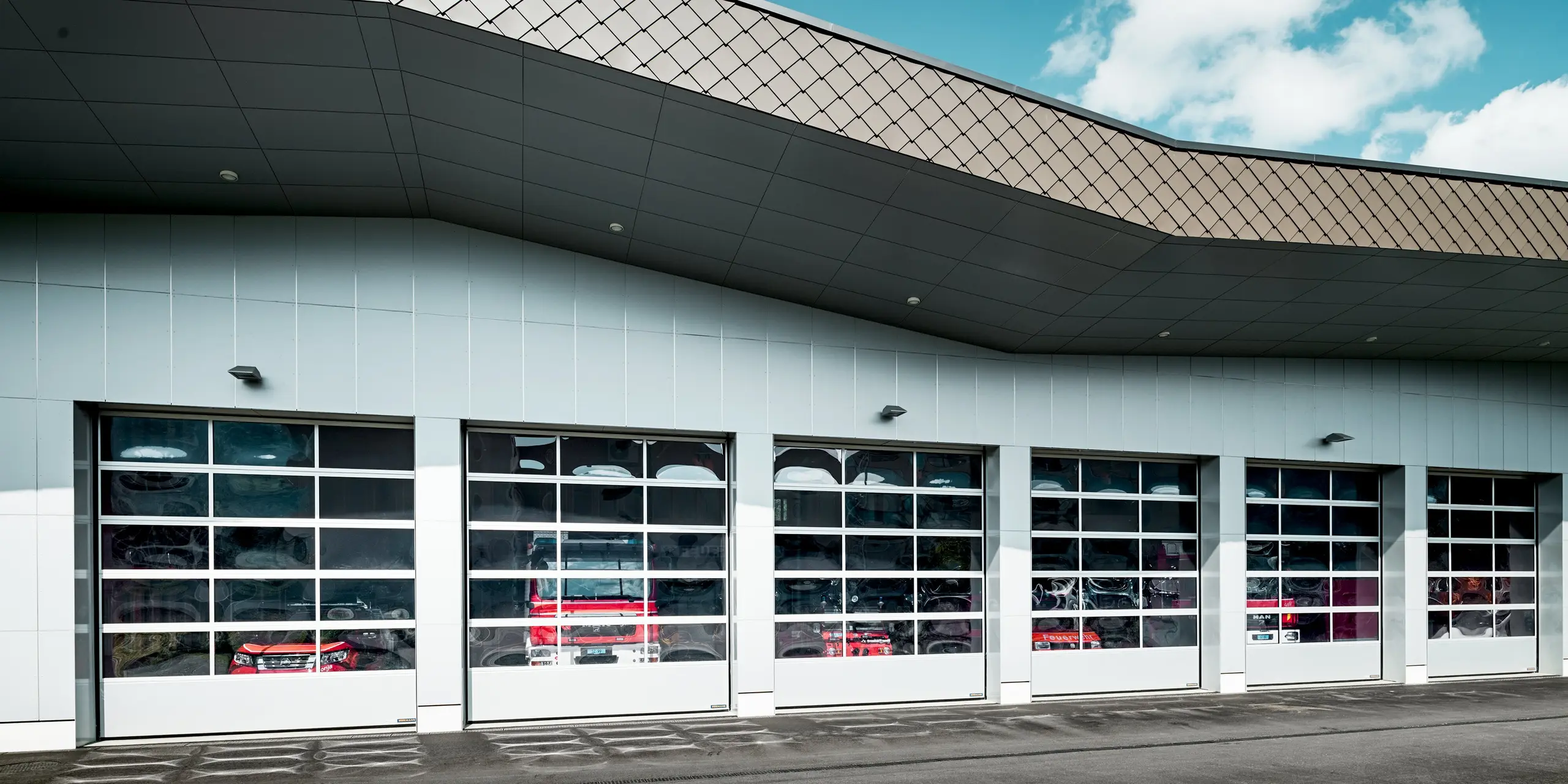 Le hall des véhicules de la caserne des pompiers de Wangen, à la façade spacieuse composée de panneaux composites en aluminium blanc P.10 Prefa et à la corniche remarquable constituée de losanges muraux PREFA 29 × 29 P.10 brun, présente une architecture affirmée. Les lignes dynamiques et la structure losangée caractéristique confèrent au bâtiment une forte présence architecturale. L'aluminium PREFA est reconnu pour sa durabilité, sa grande résistance aux intempéries et son aspect toujours impeccable.