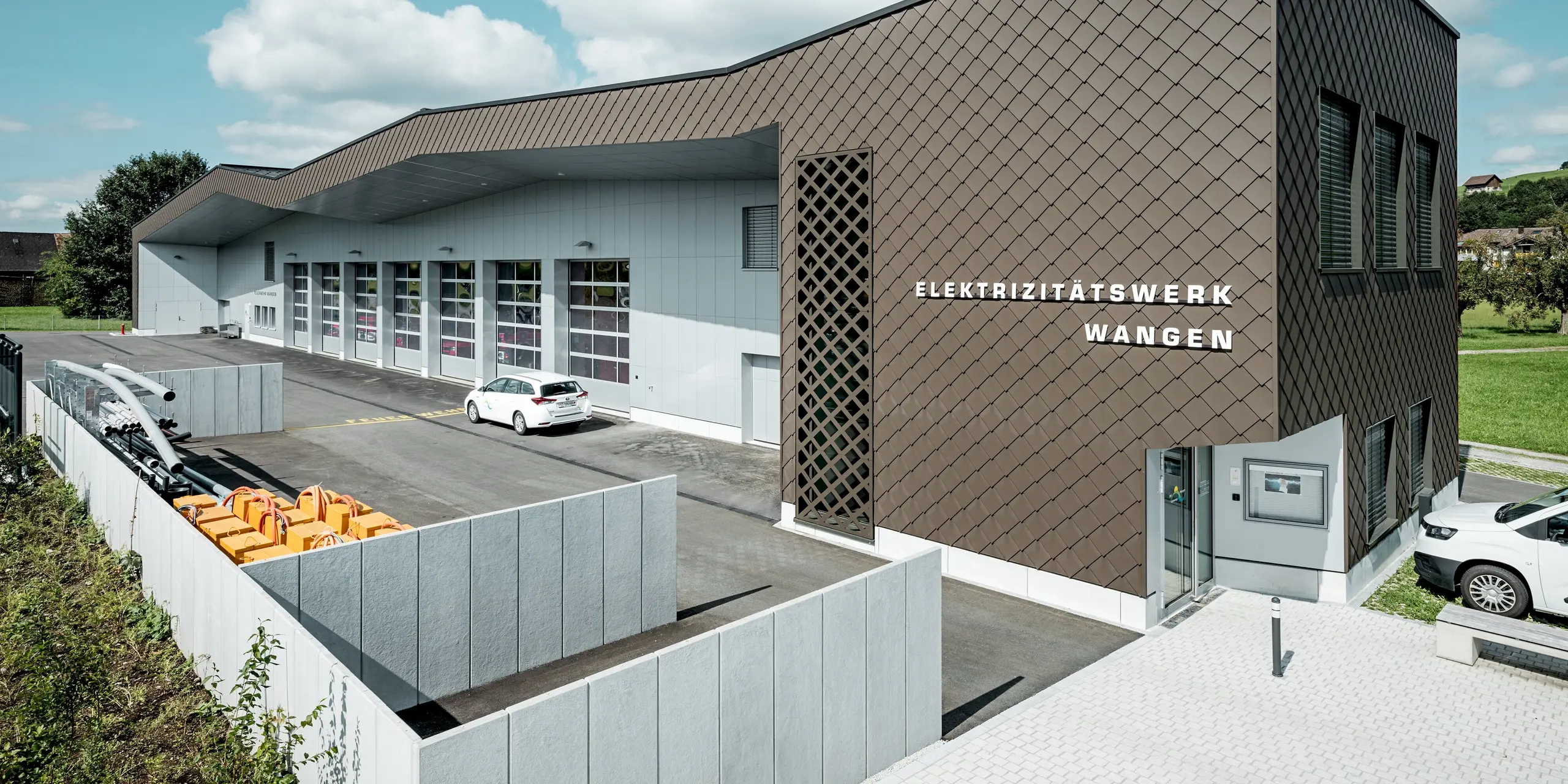À Wangen, en Suisse, une caserne de pompiers et une centrale électrique modernes présentent une enveloppe de bâtiment remarquable, composée de losanges PREFA 29 x 29 en coloris P.10 Brun. La structure dynamique en losanges confère à la façade profondeur et un aspect unique. Des panneaux composites en aluminium Prefa P.10 Blanc apportent des touches de lumière. Les produits en aluminium PREFA, d'une grande durabilité, séduisent par leur haute résistance aux intempéries, leur faible entretien et leur grande liberté de conception.