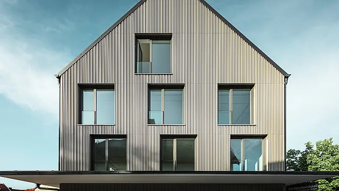 La photo montre un bâtiment moderne à Feldkirchen, conçu par l'architecte Stefan Heigl. La façade est recouverte de Prefalz de couleur bronze, tandis que le toit à pignon est recouvert de Prefalz de couleur gris noir. De grandes fenêtres rectangulaires laissent entrer beaucoup de lumière naturelle à l'intérieur. Le bâtiment allie des matériaux de haute qualité et une architecture élégante, à la fois fonctionnelle et esthétique. Cette construction moderne et l'utilisation de matériaux Prefalz confèrent au bâtiment un aspect contemporain et élégant.