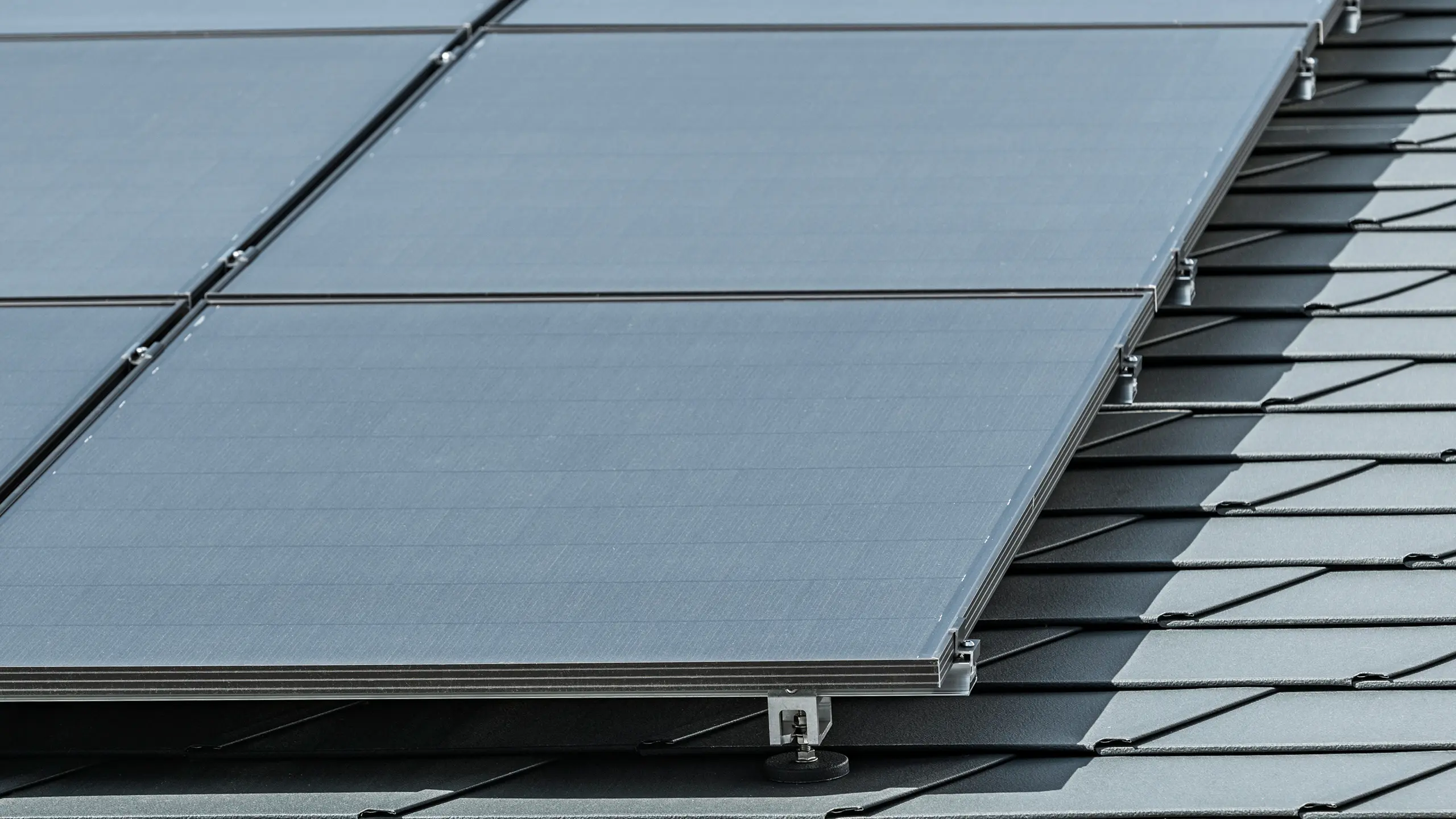 Photo de détail d'une installation photovoltaïque sur bardeaux PREFA DS.19 en P.10 anthracite, montée avec le support solaire Vario PREFA
