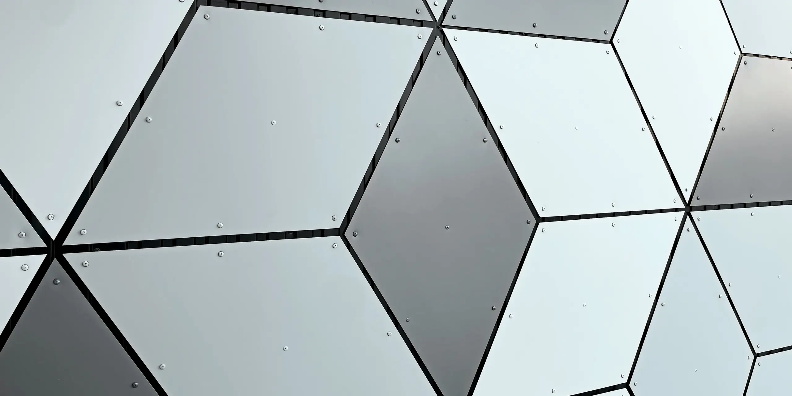 Vue détaillée de la façade de la station de téléphérique des Deux Alpes. Les panneaux composites en aluminium PREFABOND sont disposés en losange. L'association fascinante de tons blancs et gris crée un motif géométrique moderne. La fixation par vis robuste souligne la robustesse et la résistance de la construction, capable de résister aux conditions climatiques extrêmes de la haute montagne.