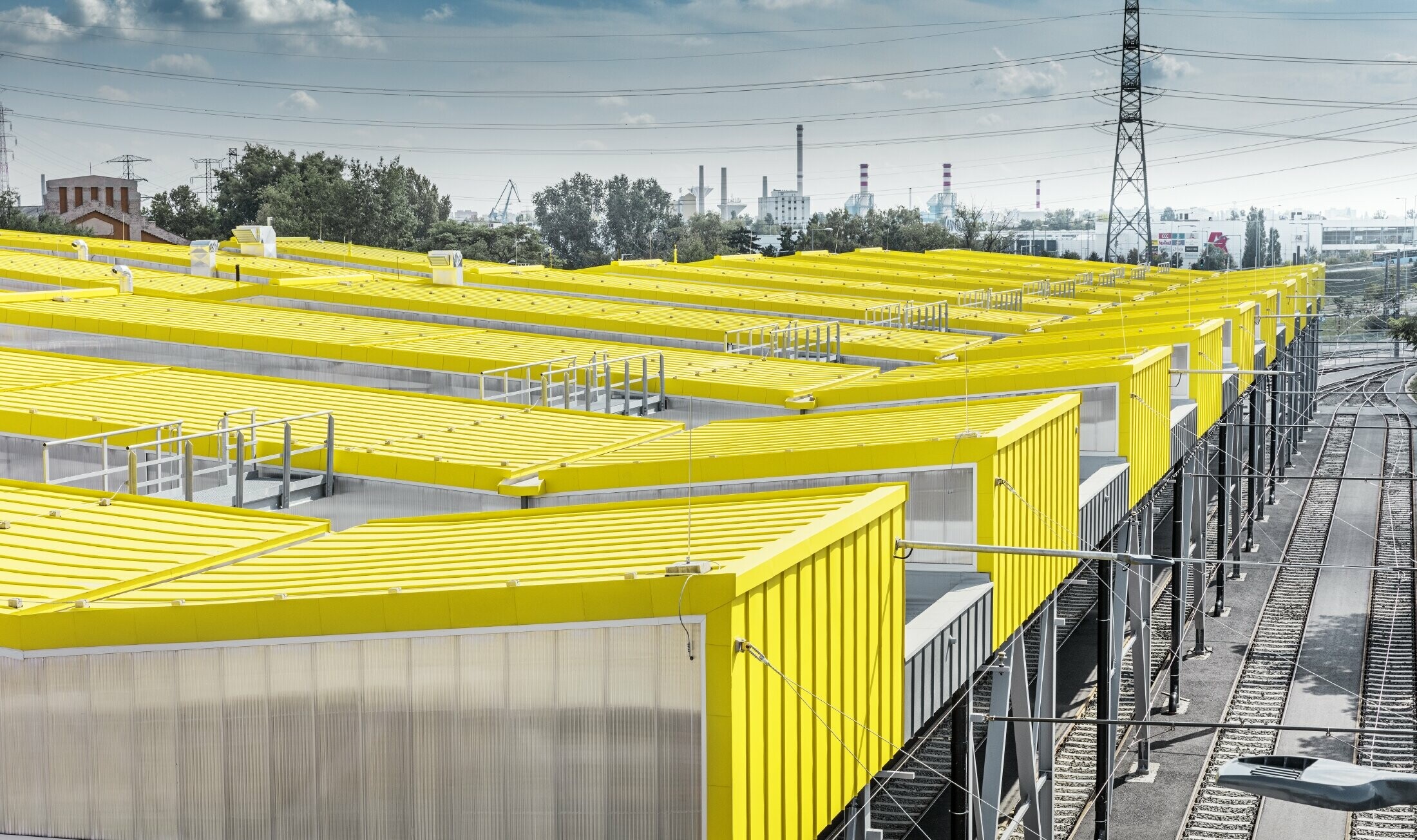 La forme du nouvel entrepôt de Budapest rappelle les tramways de la ville. Il a été habillé avec un toit à joint debout de PREFA couleur jaune signalisation, RAL 1023.