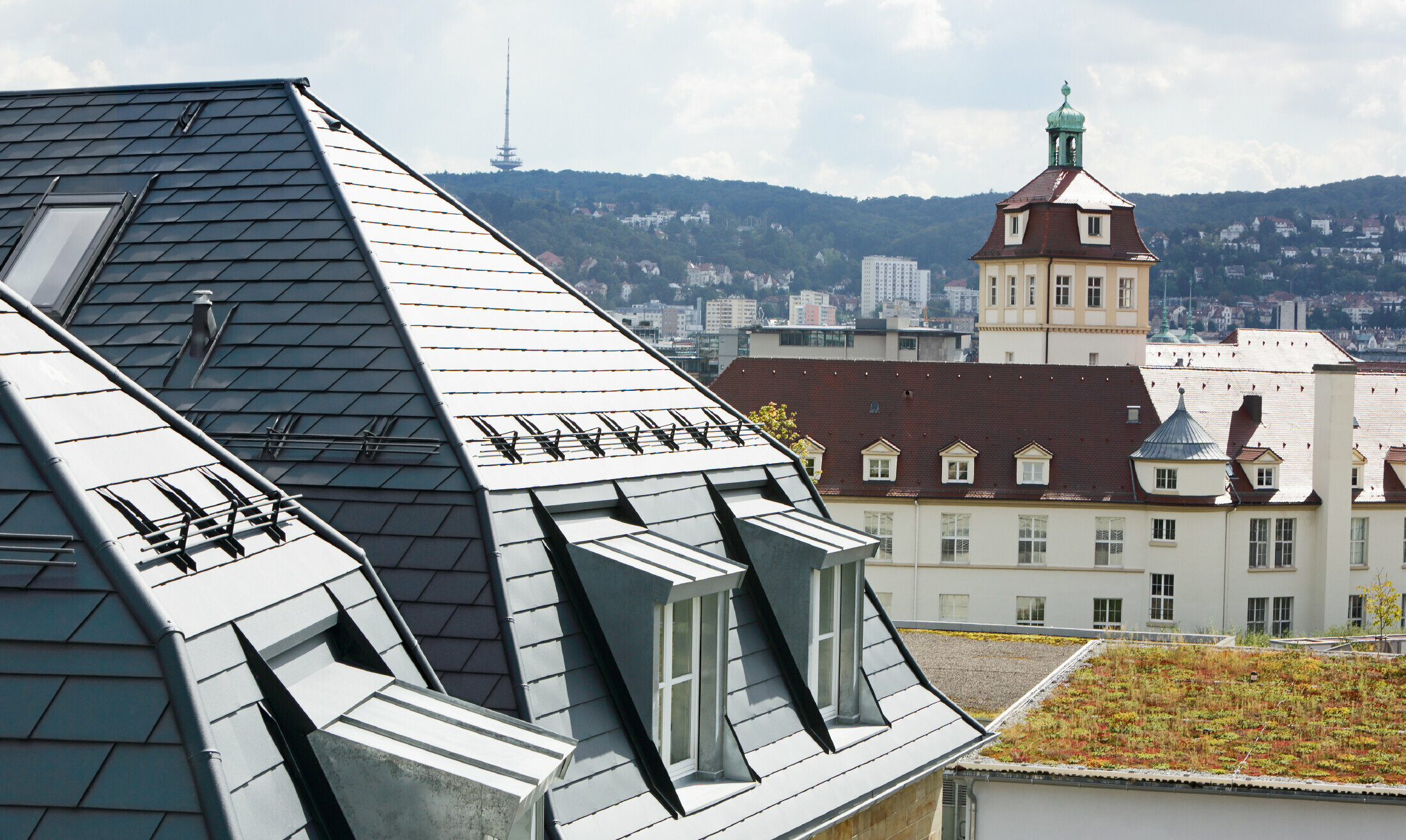Maison de ville ancienne à Stuttgart, avec toit mansardé recouvert de bardeaux en aluminium PREFA en P.10 anthracite et nombreuses fenêtres-lucarnes