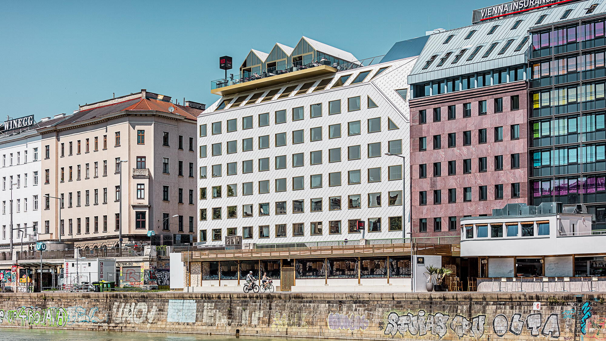L'hôtel vu de côté et son environnement bâti, le canal du Danube s'étendant juste devant lui.