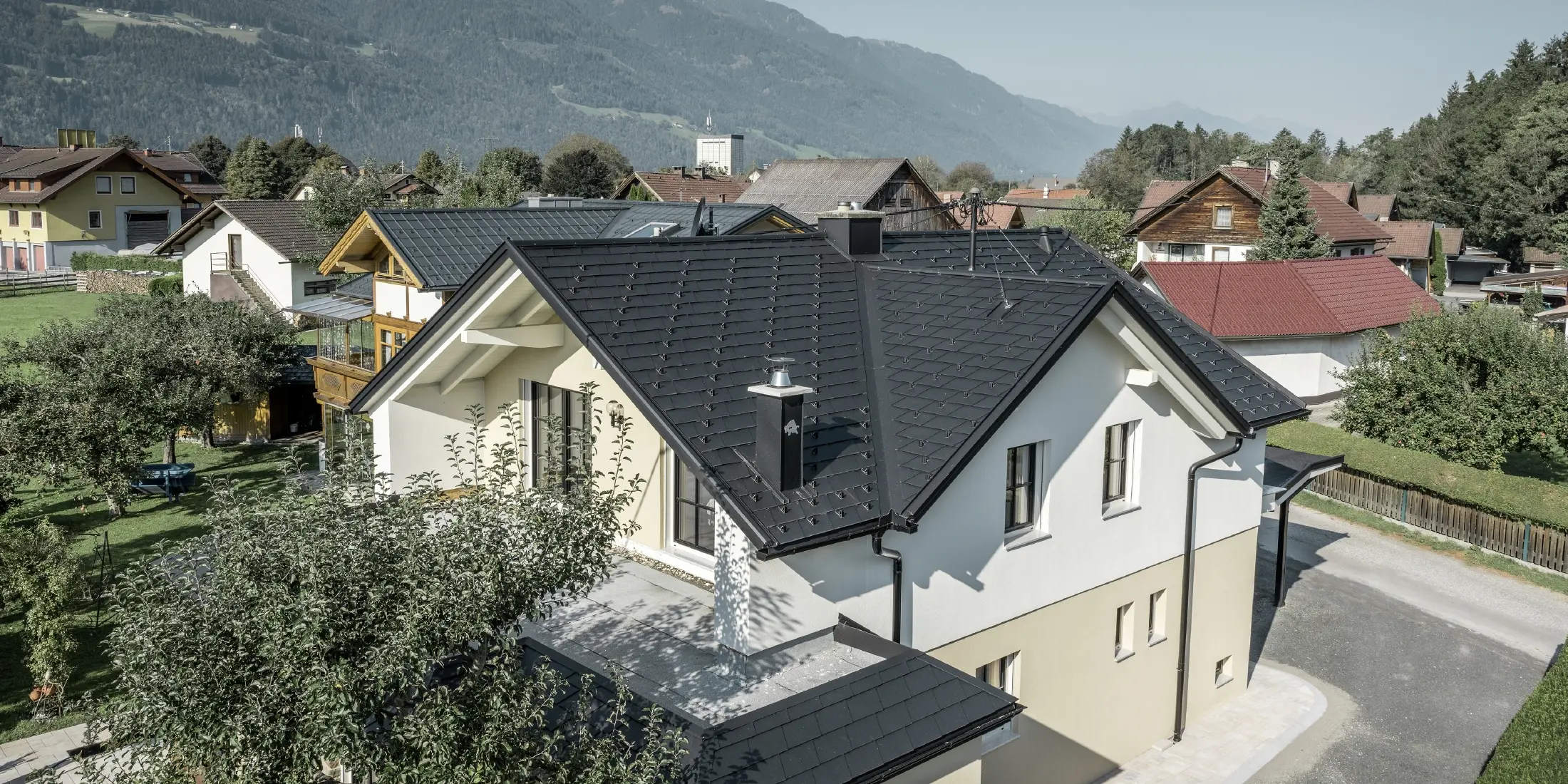 Maison individuelle traditionnelle avec toit en bâtière et grande lucarne, récemment rénovée. La toiture est recouverte de bardeaux noirs PREFA.