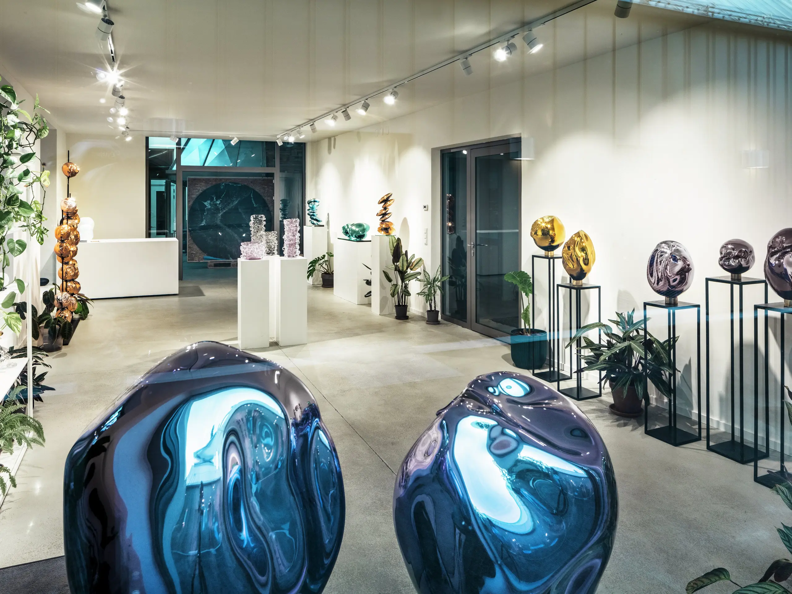 Vue intérieure du Studio Comploj à Vienne avec une exposition d'objets en verre faits à la main. L'espace galerie moderne combine art, design et artisanat dans un environnement élégant.