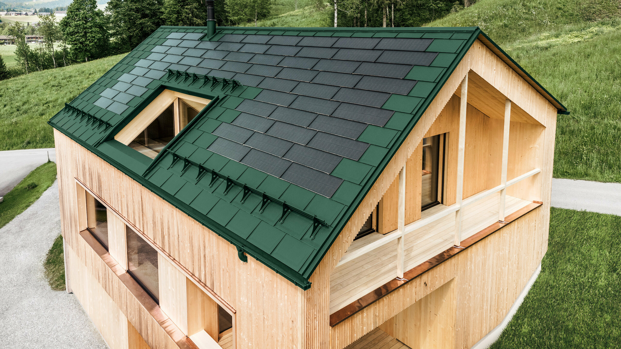 Maison individuelle dans la localité autrichienne d'Egg avec le panneau solaire de toiture PREFA et le panneau de toiture R.16 en vert mousse, combinés à une façade en bois