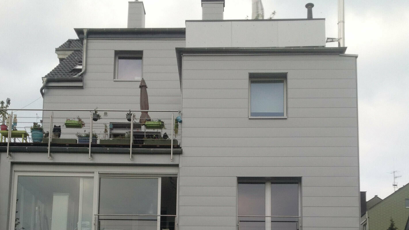 Immeuble d’habitation avec toit plat et terrasse, avec façade récemment rénovée à l’aide de Sidings PREFA