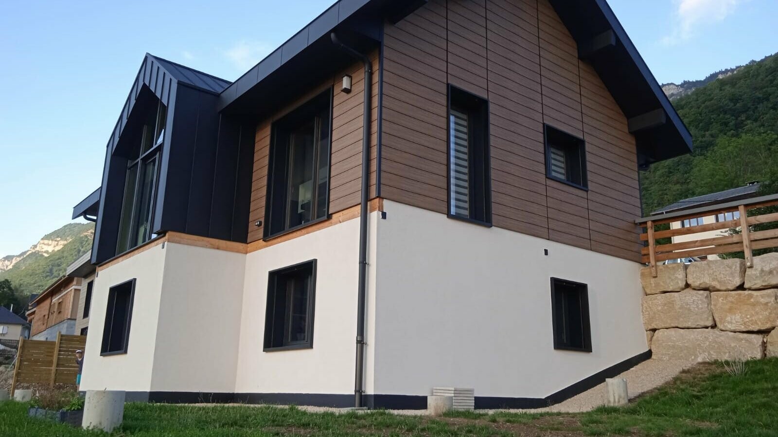 Vue d'ensemble de cette belle maison individuelle dont la façade est couverte de Siding PREFA, teinte noyer foncé et la couverture en joint debout Prefalz