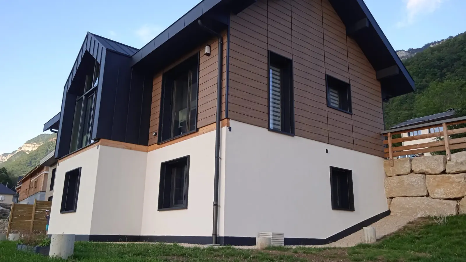 Vue d'ensemble de cette belle maison individuelle dont la façade est couverte de Siding PREFA, teinte noyer foncé et la couverture en joint debout Prefalz