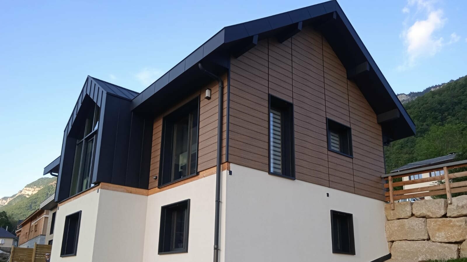 Vue d'ensemble de cette belle maison individuelle dont la façade est couverte de Siding PREFA, teinte noyer foncé et la couverture en joint debout Prefalz