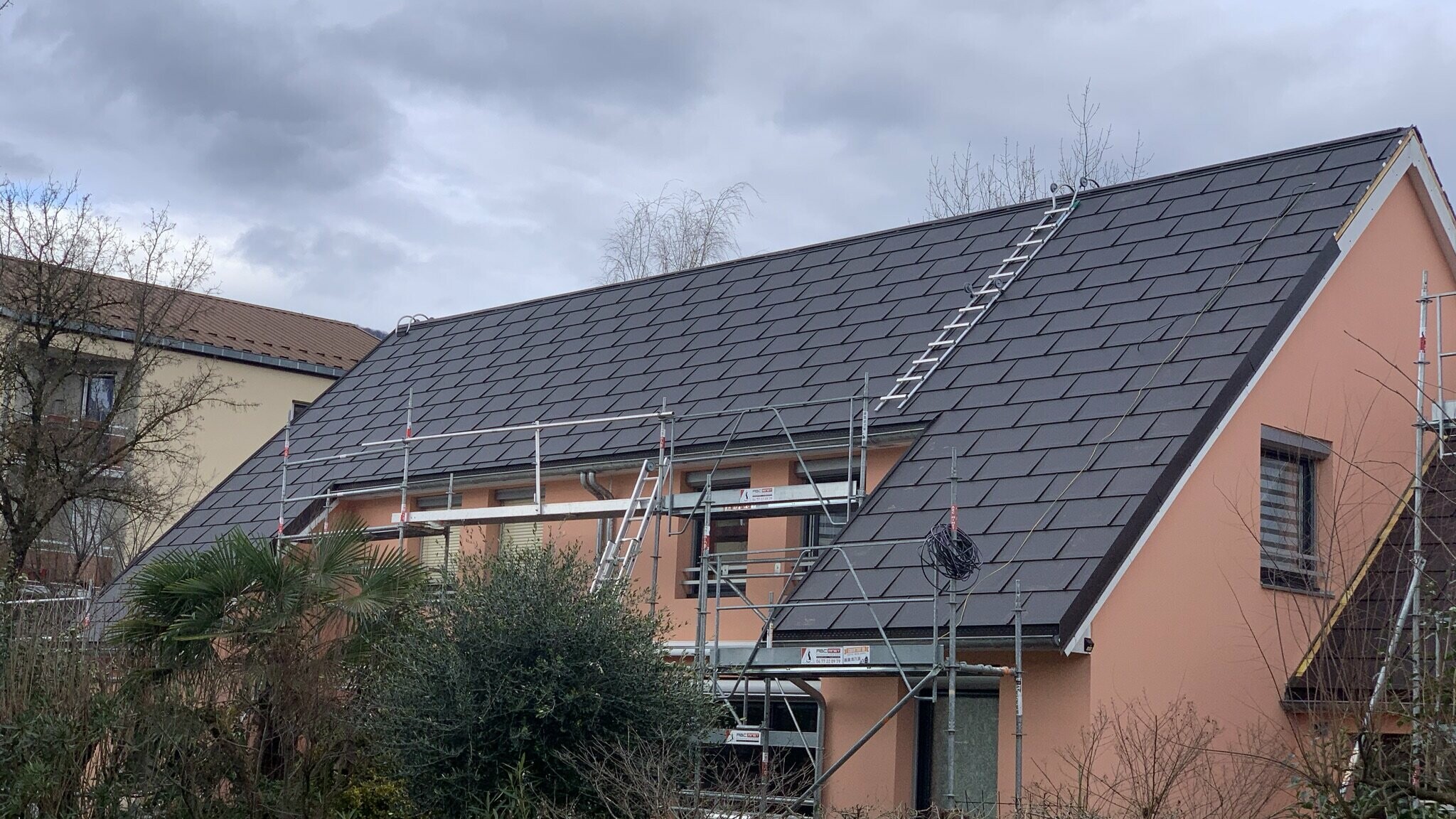 Vue de côté de la maison individuelle rénovée grâce aux R.16 PREFA dans la teinte P.10 brun noisette