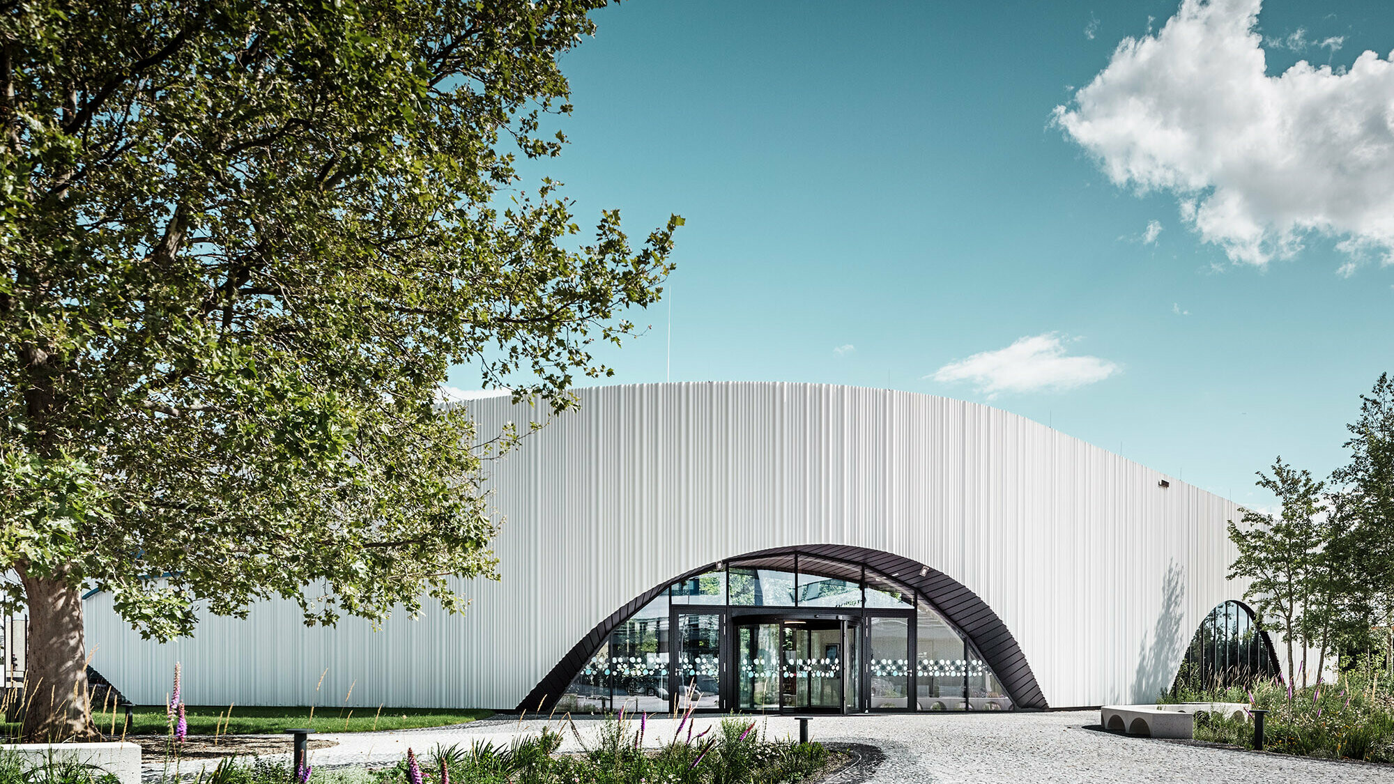 Vue normale du restaurant Walters avec l'une de ses fenêtres en arc de cercle au milieu d'un environnement verdoyant.
