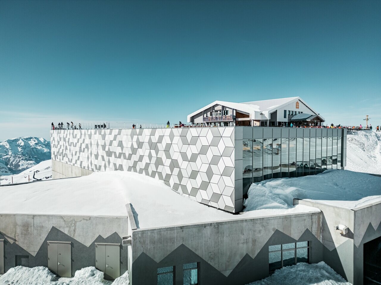 Vue d'une des stations du nouveau téléphérique Le Jandri de la station Les 2 Alpes, recouverte de panneaux composites en aluminium PREFABOND façonné en losanges de trois couleurs différentes : blanc Prefa, blanc pur et argent fumé.