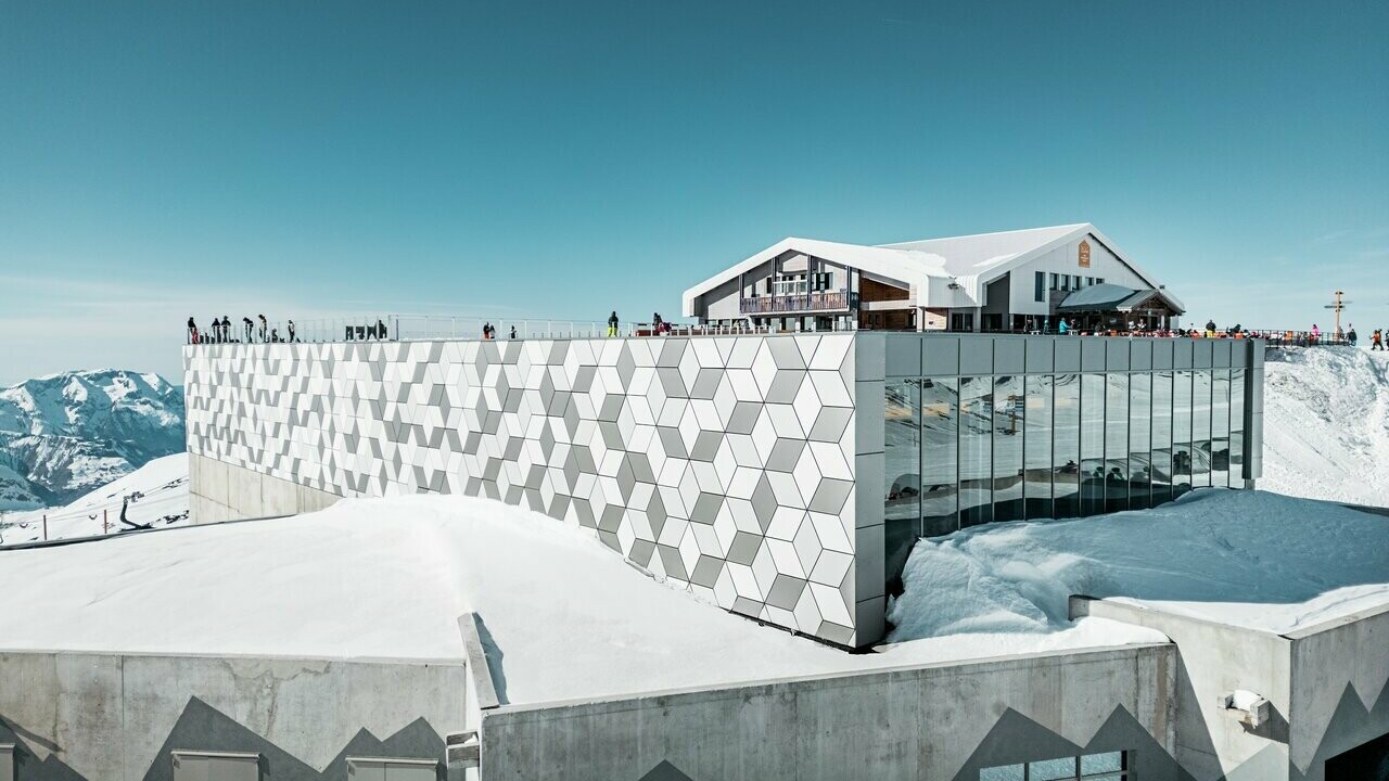 Vue d'une des stations du nouveau téléphérique Le Jandri de la station Les 2 Alpes, recouverte de panneaux composites en aluminium PREFABOND façonné en losanges de trois couleurs différentes : blanc Prefa, blanc pur et argent fumé.