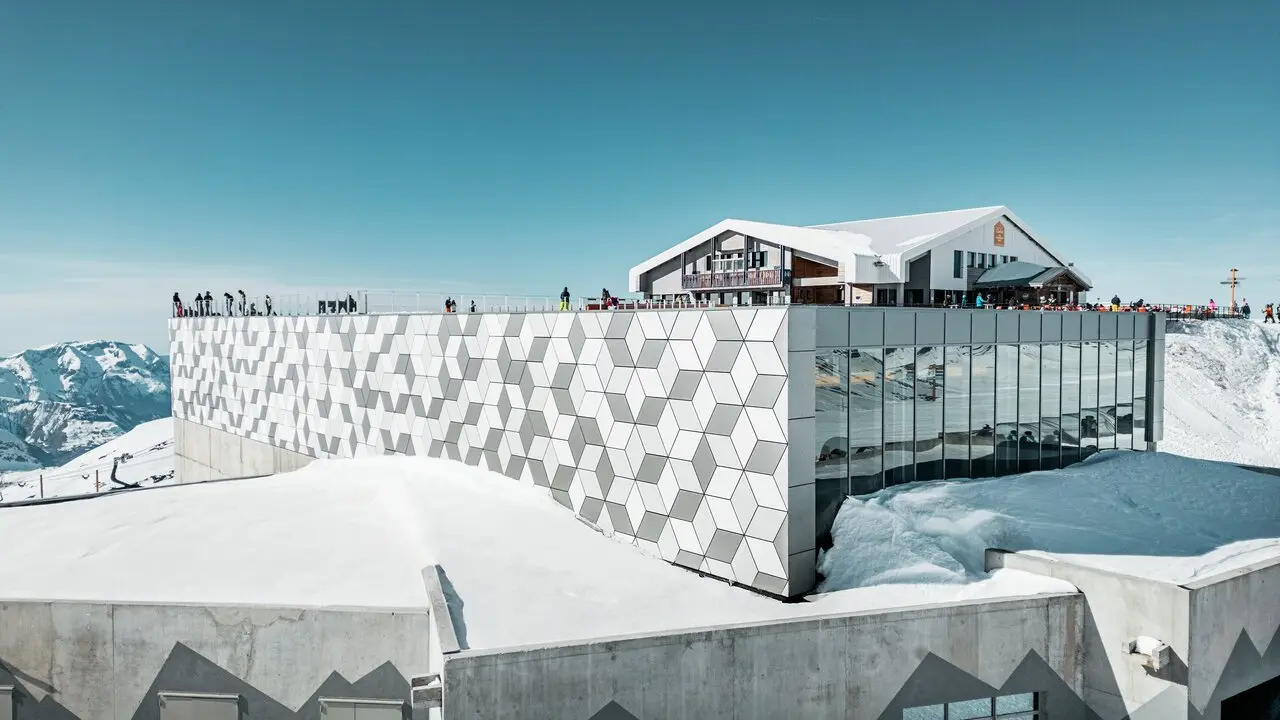 Vue d'une des stations du nouveau téléphérique Le Jandri de la station Les 2 Alpes, recouverte de panneaux composites en aluminium PREFABOND façonné en losanges de trois couleurs différentes : blanc Prefa, blanc pur et argent fumé.