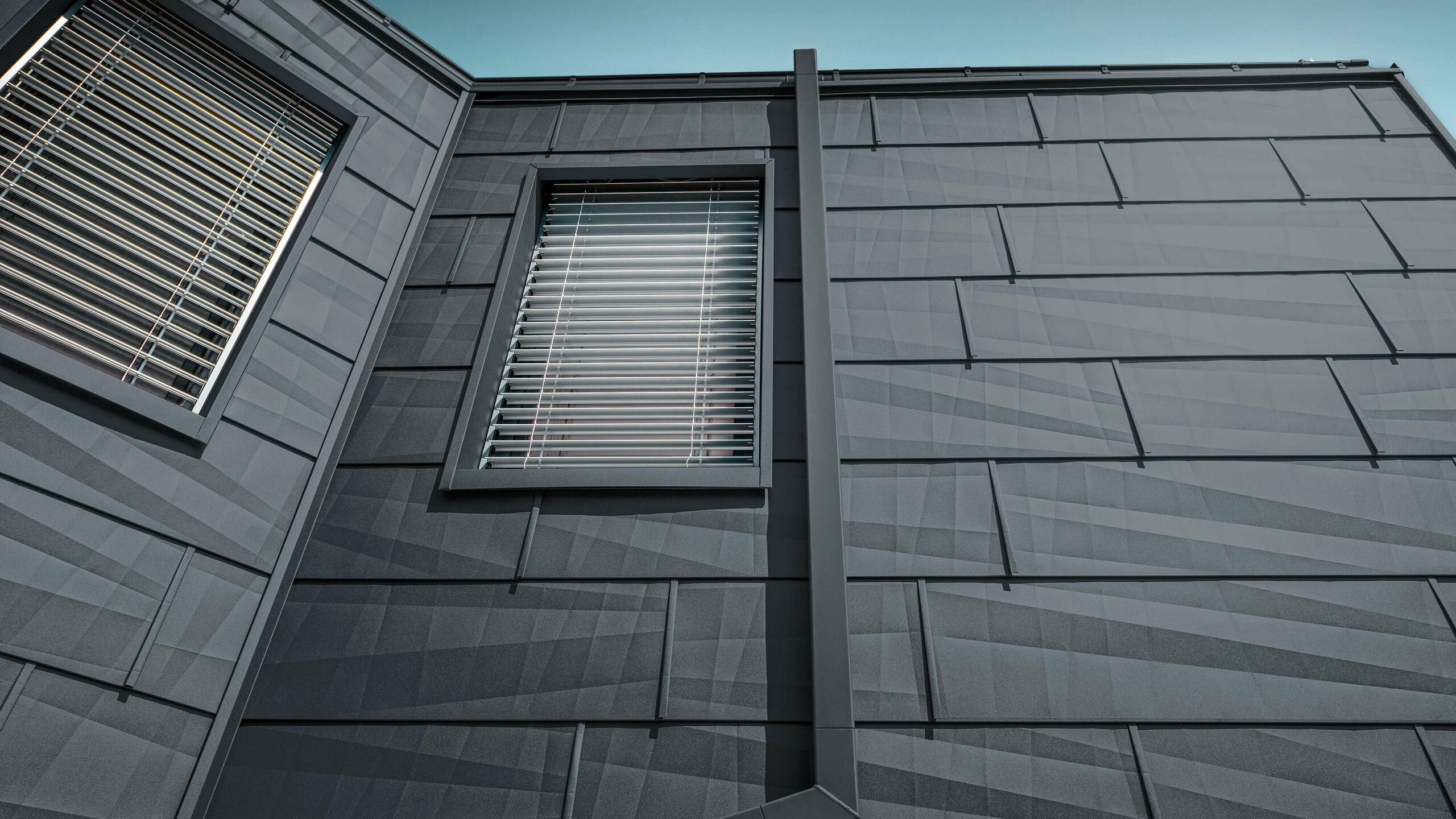 Façade revêtue du panneau de façade FX.12 PREFA couleur anthracite, panneauxen ’aluminium sur la façade avec tuyau de descente carré couleur anthracite de PREFA.