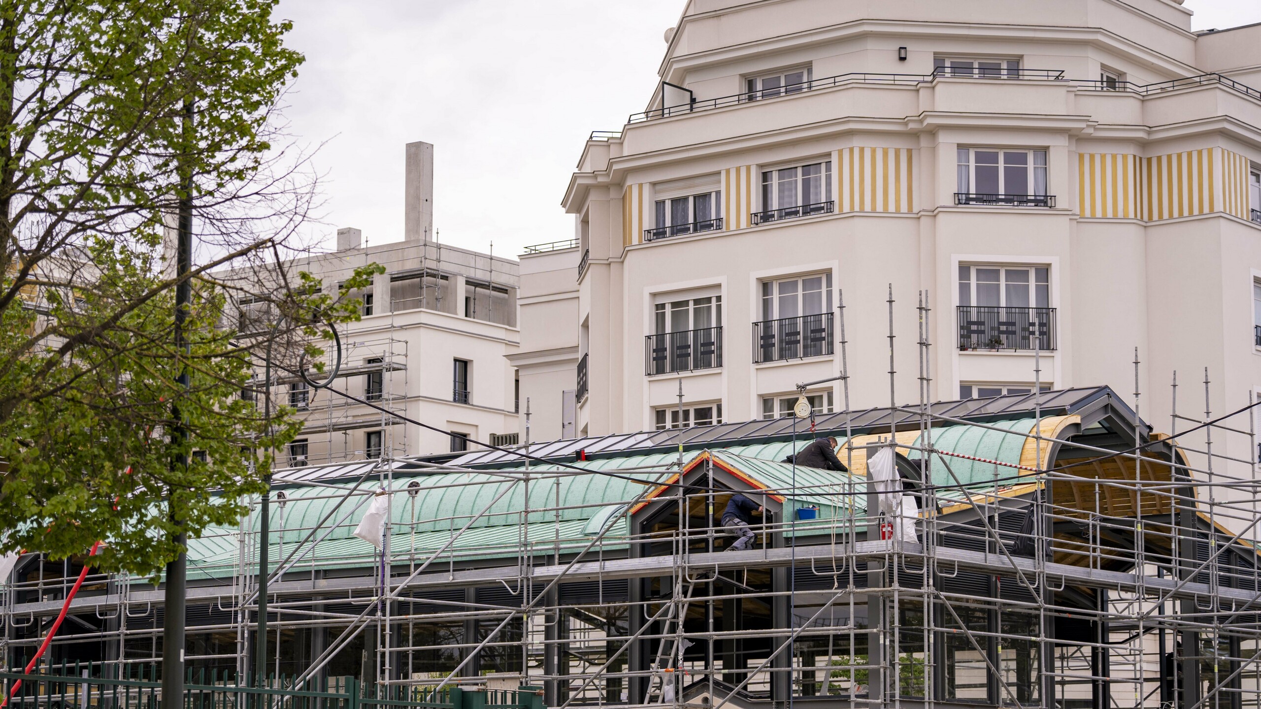 Photo prise du sol, devant la halle de Clamart en travaux. On y voit déjà une partie de la toiture rénovée en aluminium PREFA, cachée derrière les échafaudages. 
