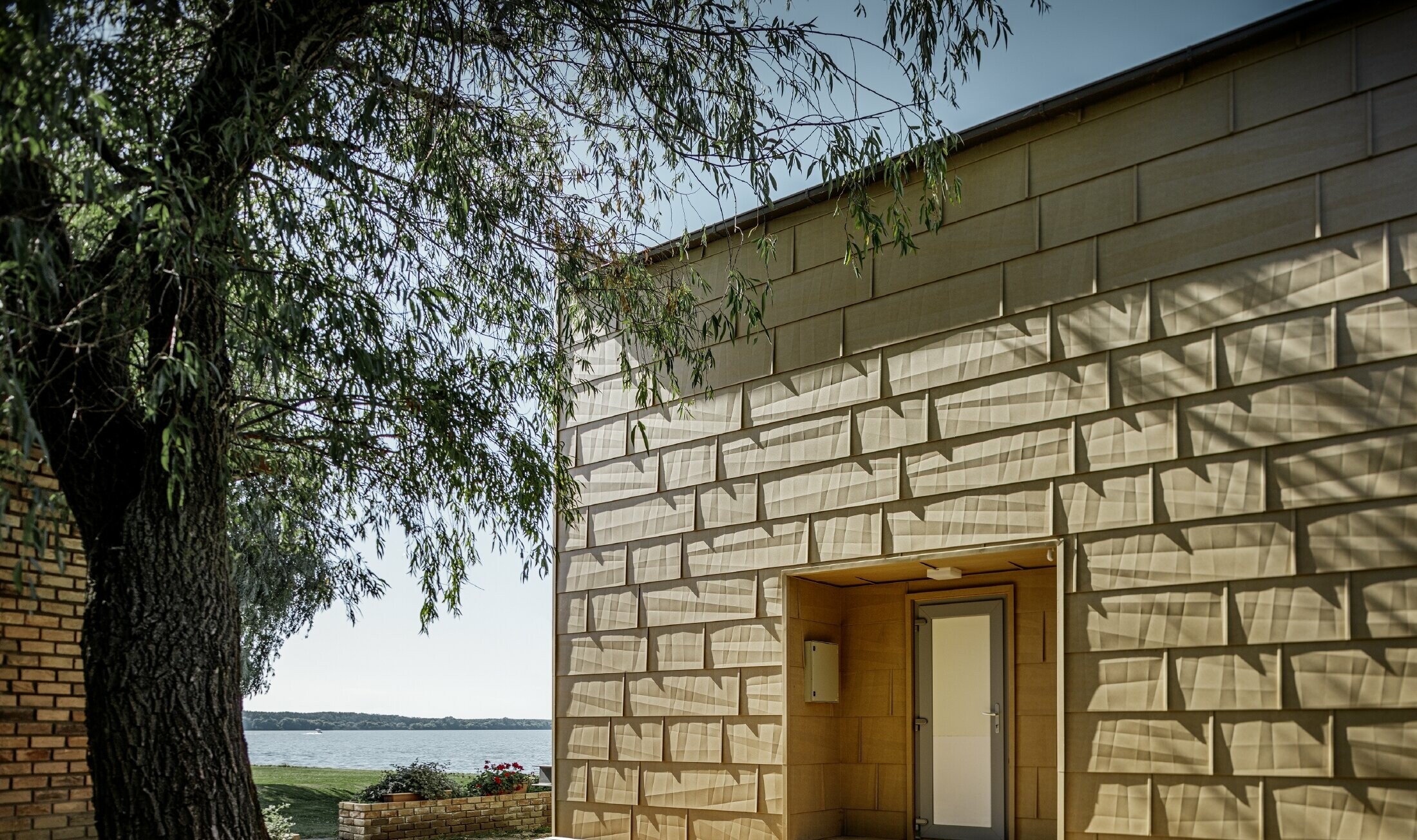 Maison secondaire moderne au toit plat et aux grandes baies vitrées donnant sur le lac — Façades en aluminium PREFA de couleur brun sable aux arêtes prononcées