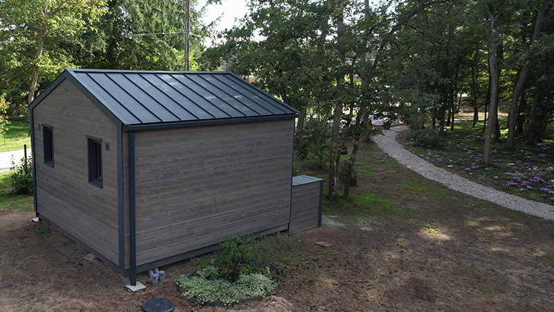 Photo d'un lodge, niché au cœur de la forêt, dont la toiture a été réalisé en aluminium PREFA dans la teinte P.10 anthracite.