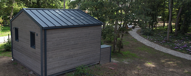 Photo d'un lodge, niché au cœur de la forêt, dont la toiture a été réalisé en aluminium PREFA dans la teinte P.10 anthracite.