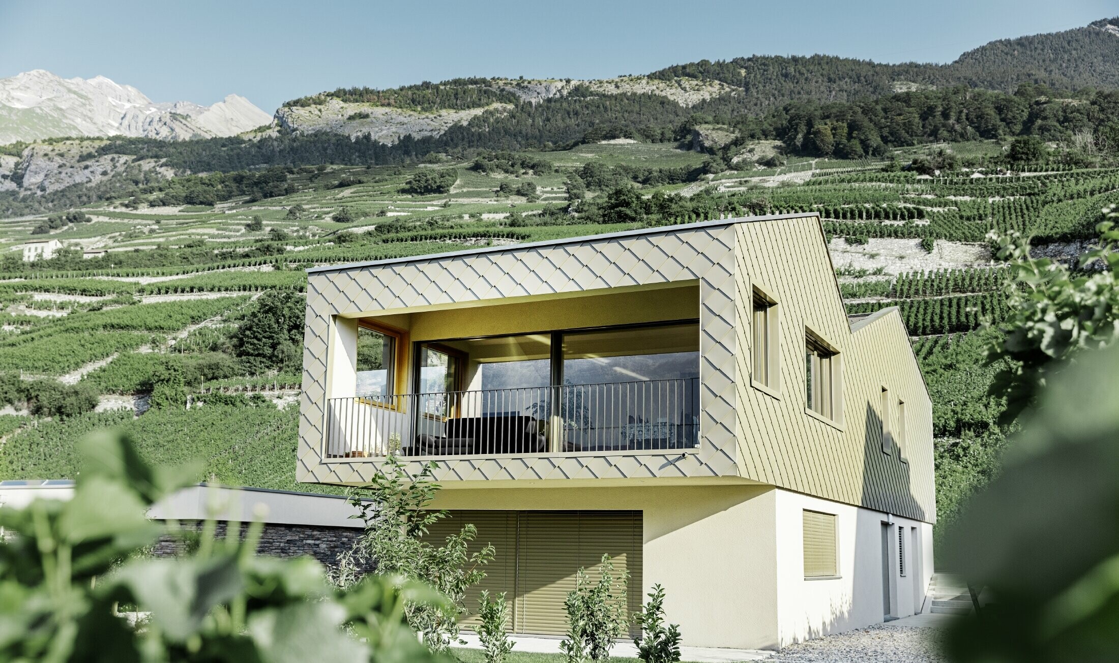 Maison individuelle moderne au cœur des vignobles de la vallée du Rhône avec quatre pentes de toit et grand balcon couvert — Façade habillée de losanges PREFA de couleur bronze
