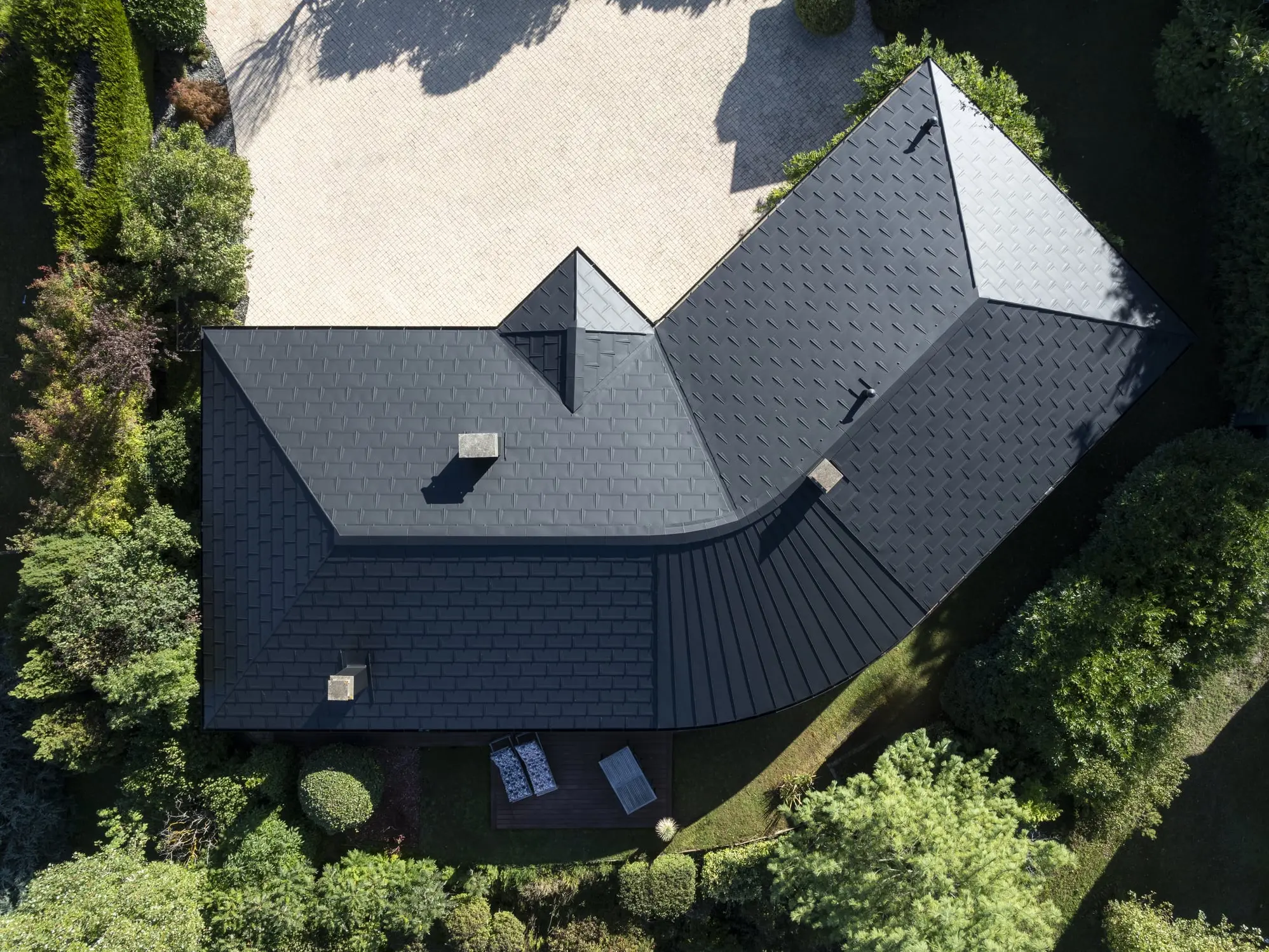 Vue de drone de cette maison individuelle récemment rénovée avec les produits en aluminium PREFA : gouttière demi-ronde, R.16 et joint debout Prefalz en P.10 noir