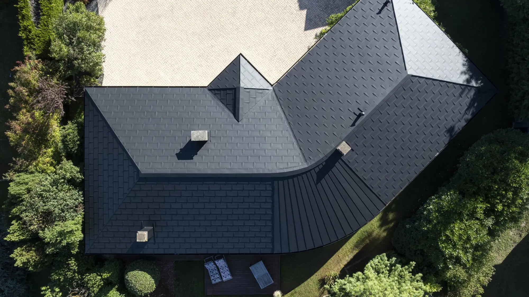 Vue de drone de cette maison individuelle récemment rénovée avec les produits en aluminium PREFA : gouttière demi-ronde, R.16 et joint debout Prefalz en P.10 noir