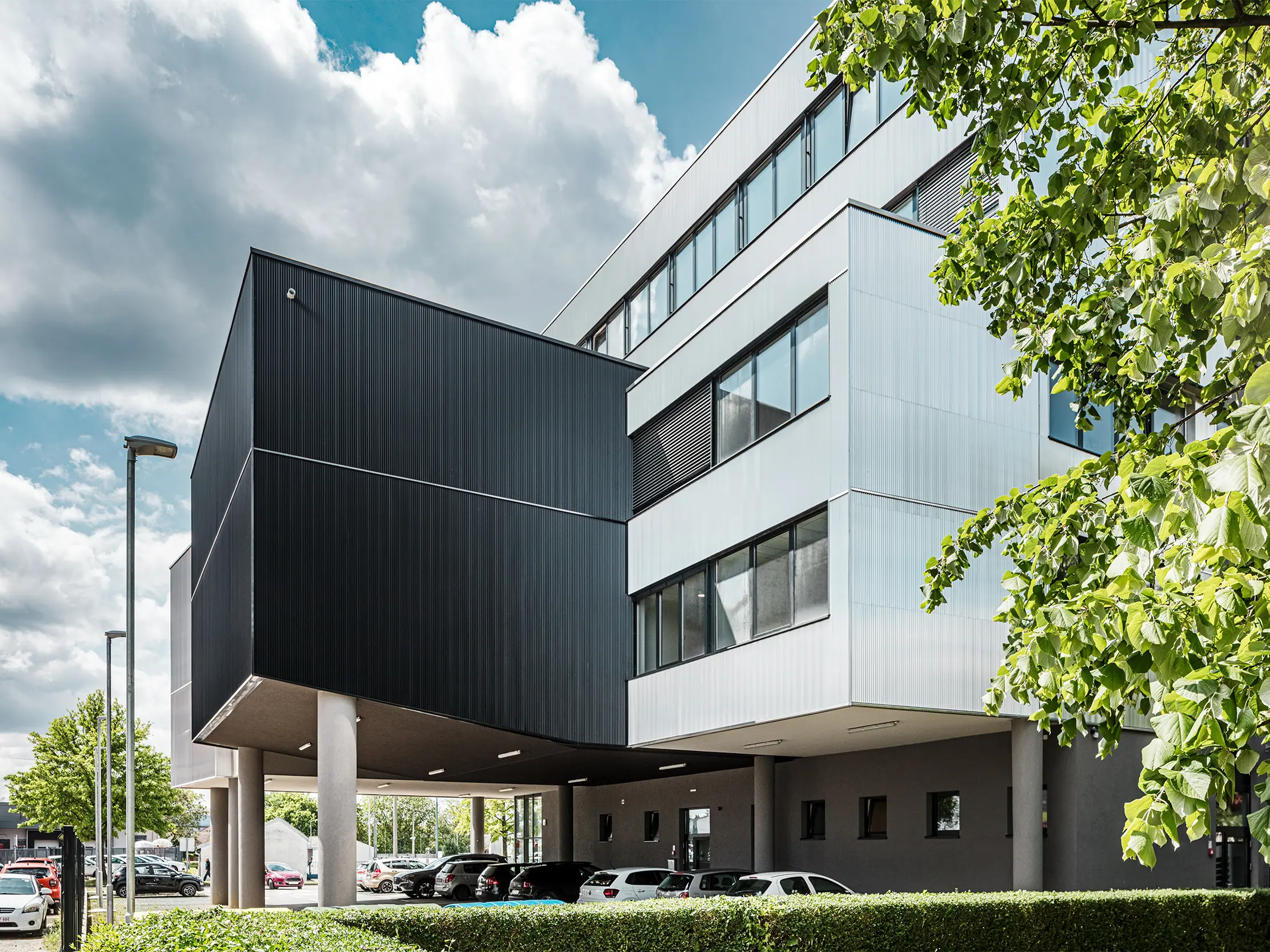 Le bâtiment moderne de l’école de musique de Bjelovar, en Croatie, se distingue par une façade en aluminium remarquable réalisée avec les profils extrudés PREFA « Triangle ». Les surfaces de façade anodisées en noir et en argent créent des contrastes architecturaux affirmés et confèrent au bâtiment caractère et profondeur. Posés verticalement, les profils génèrent une structure élégante avec un jeu captivant d’ombre et de lumière. Grâce à la surface en aluminium robuste et résistante à la corrosion, les éléments de façade sont particulièrement durables et faciles d’entretien. La fixation dissimulée assure un rendu homogène et haut de gamme. Cette façade PREFA rapportée et ventilée allie design, technique et fonctionnalité.