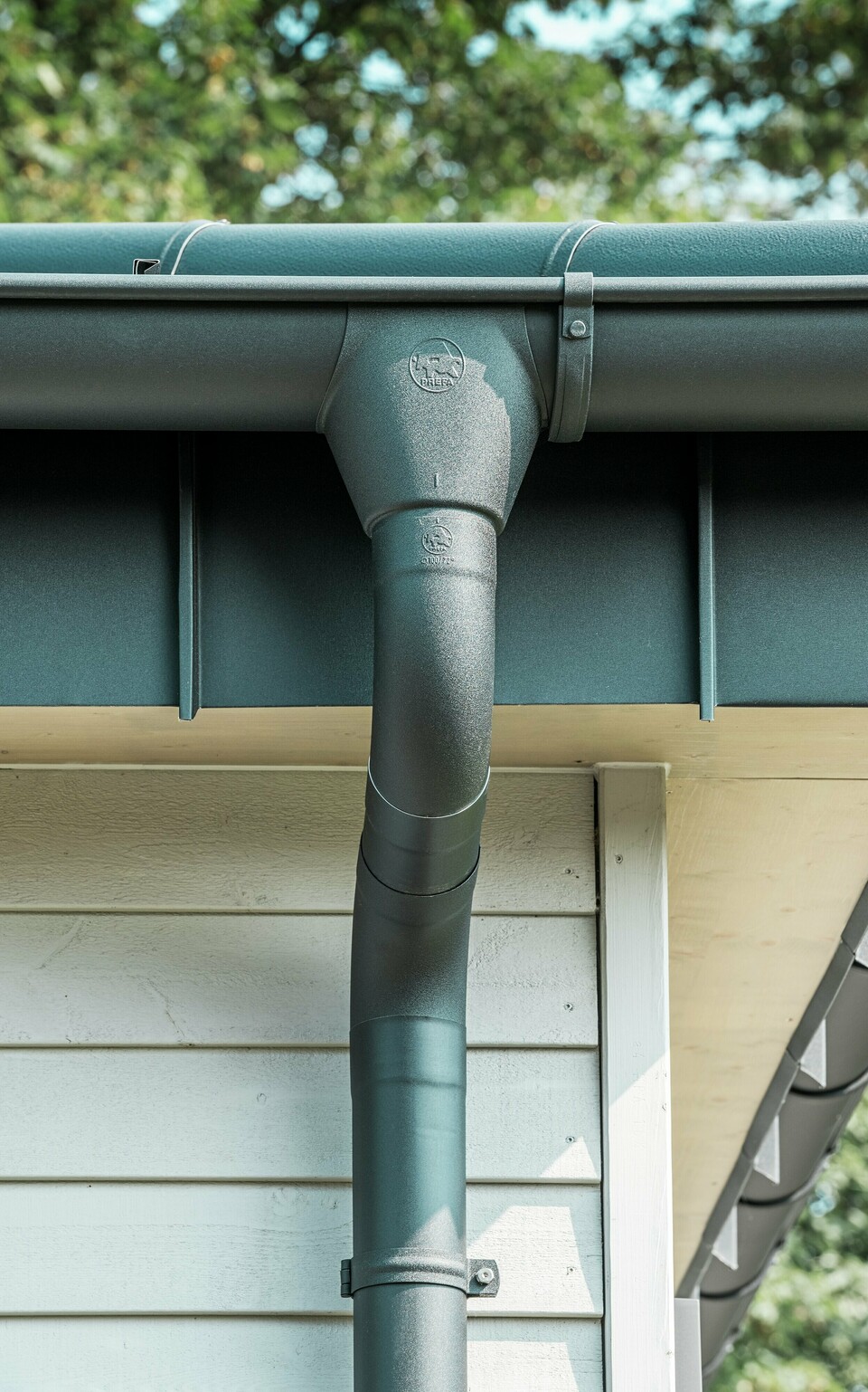 Gros plan du robuste système d'évacuation des eaux pluviales PREFA d'un bungalow à Rommerskirchen. La gouttière et le tuyau de descente de haute qualité P.10 noir offrent une protection optimale contre les intempéries. Durabilité et fonctionnalité se combinent avec un design élégant en aluminium.