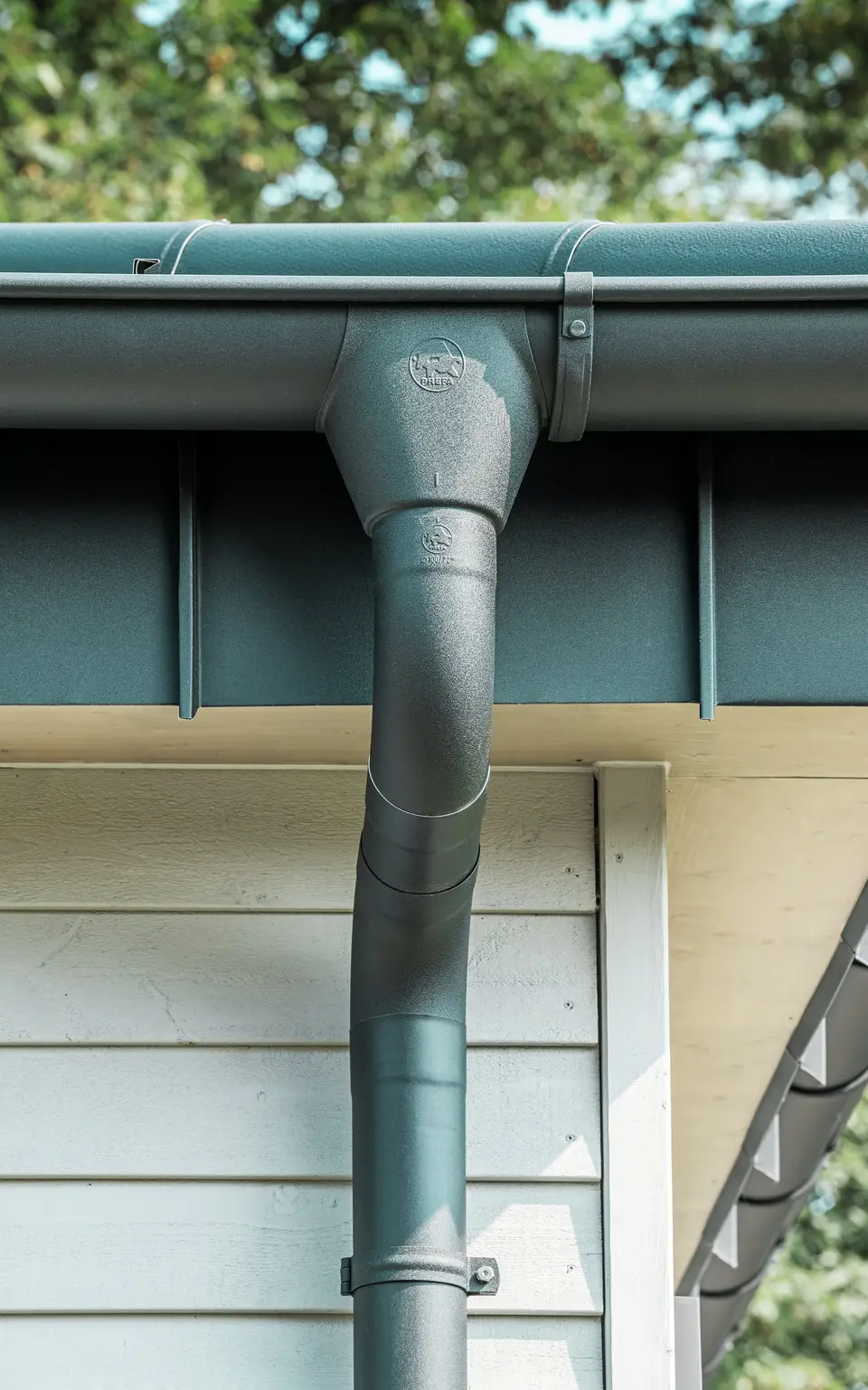 Gros plan du robuste système d'évacuation des eaux pluviales PREFA d'un bungalow à Rommerskirchen. La gouttière et le tuyau de descente de haute qualité P.10 noir offrent une protection optimale contre les intempéries. Durabilité et fonctionnalité se combinent avec un design élégant en aluminium.