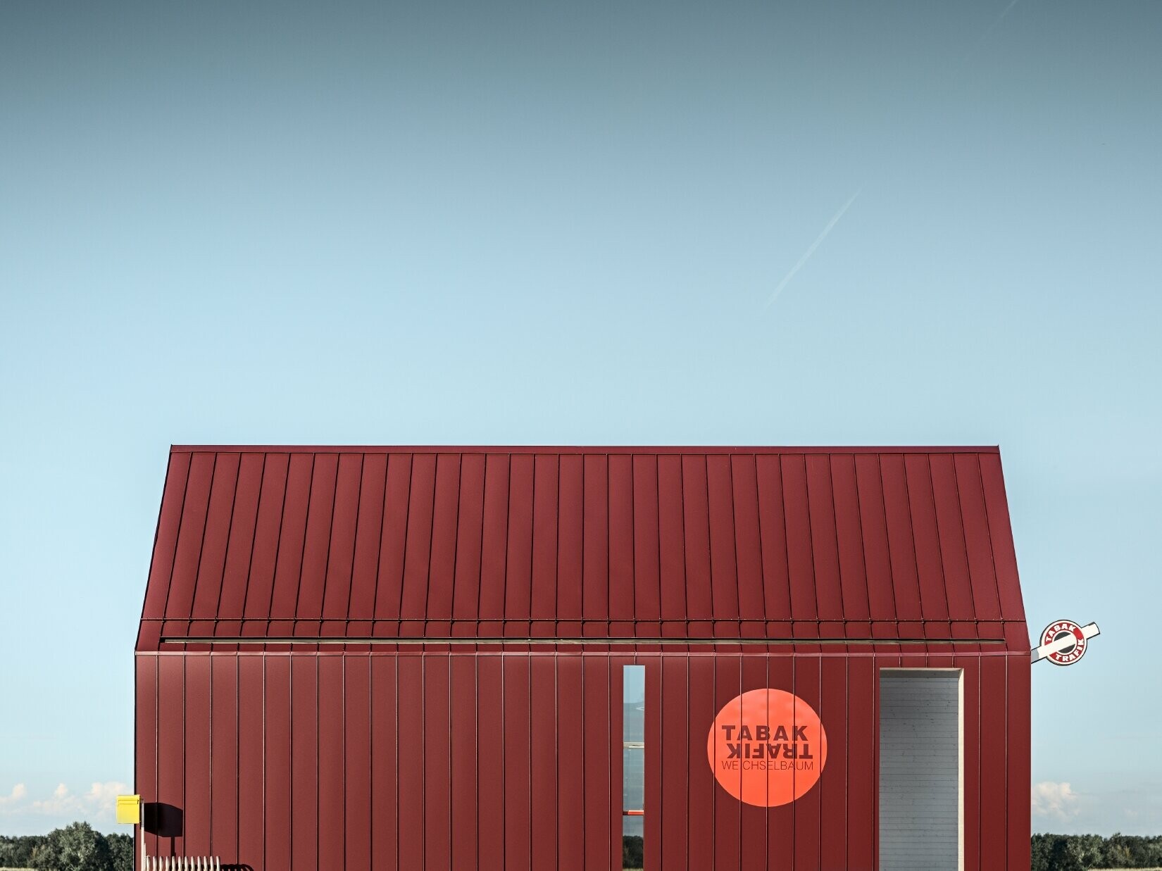 Bureau de tabac moderne au toit à deux versants sans saillie de façade — Enveloppe en aluminium PREFA à joints debout et joints angulaires rouge-noir (couleur spéciale)