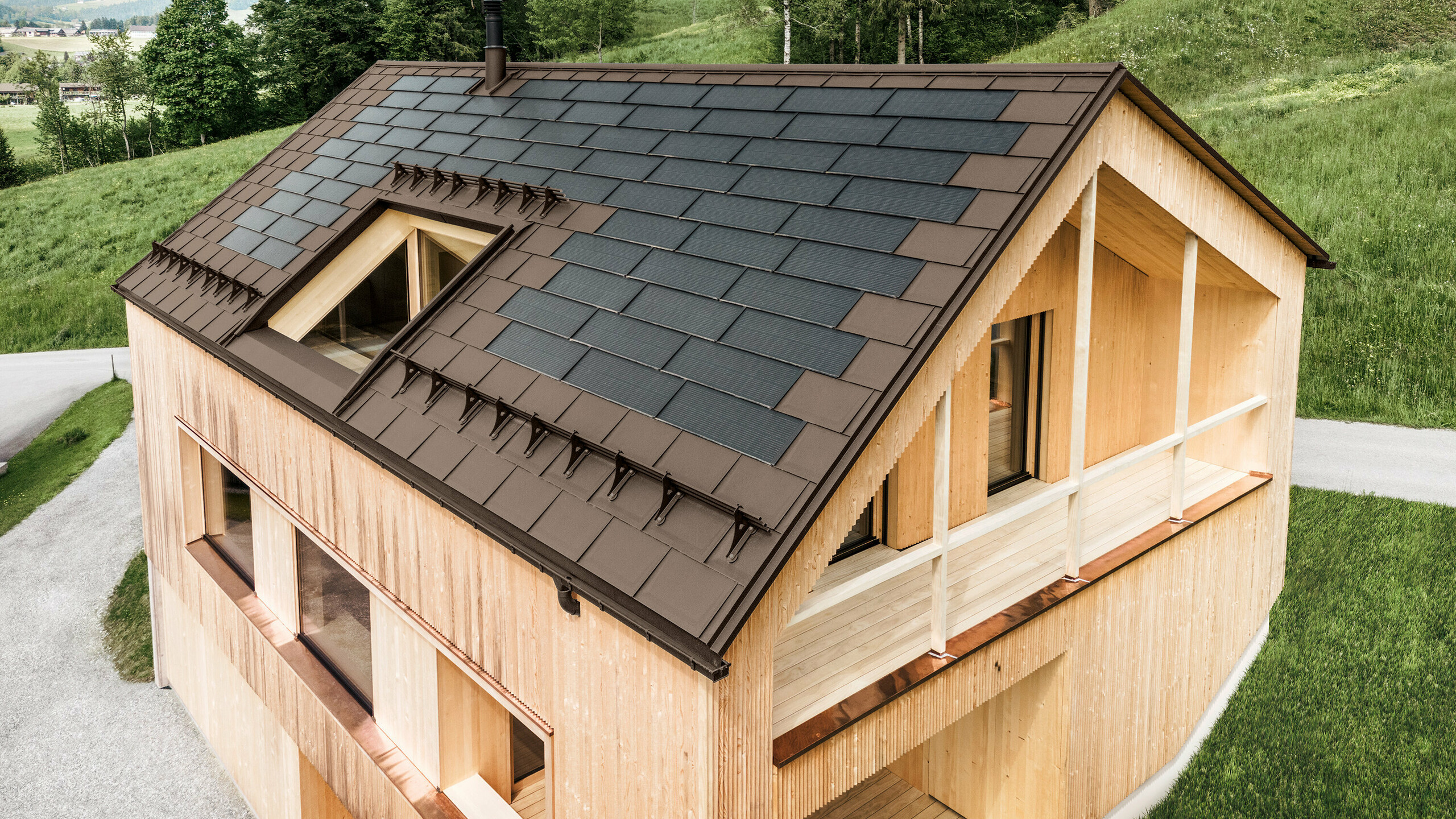 Maison individuelle dans la localité autrichienne d'Egg avec le panneau solaire de toiture PREFA et le panneau de toiture R.16 en brun, combinés à une façade en bois