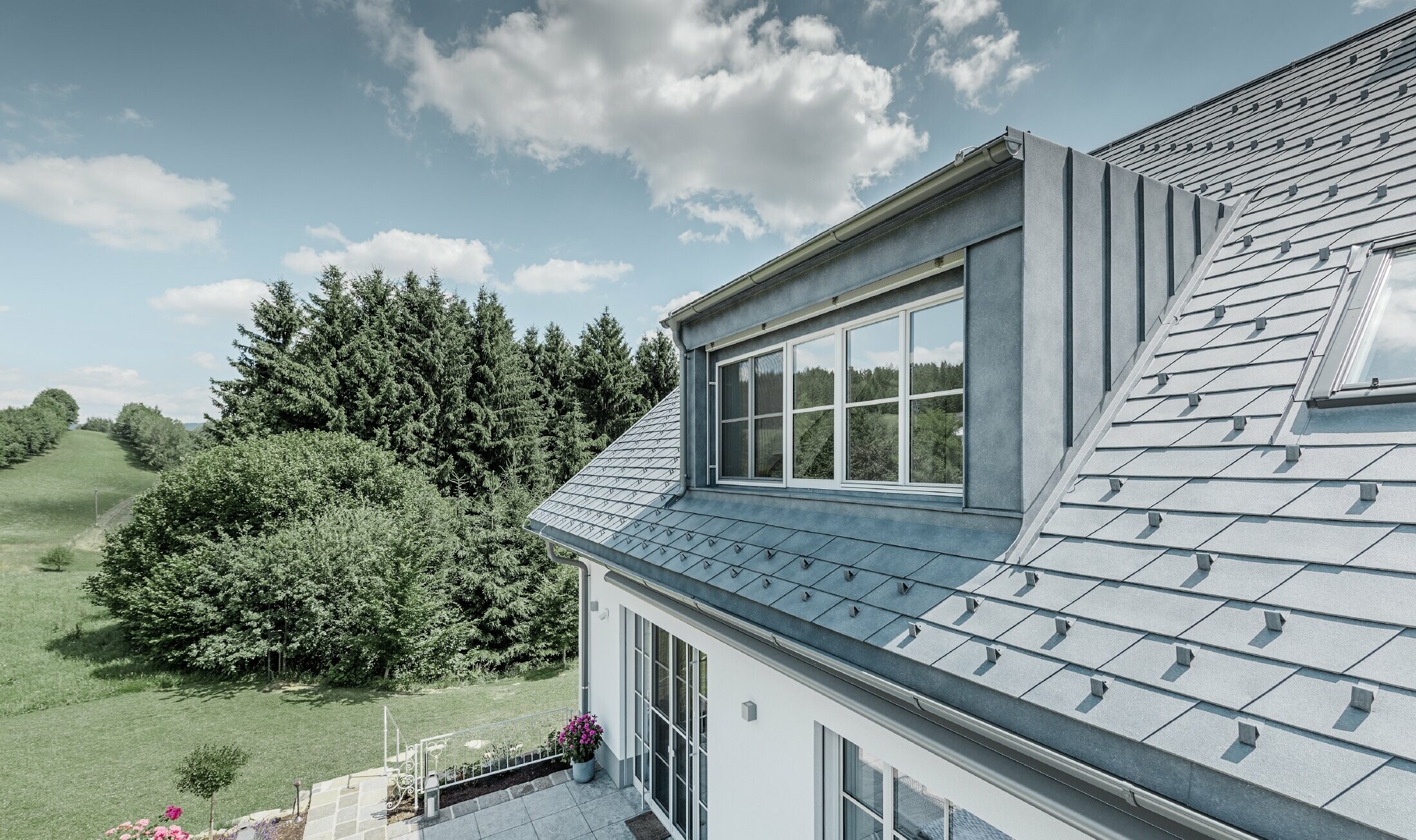 Lucarne de la maison individuelle rénovée avec le bardeau de toiture PREFA couleur gris pierre. La lucarne est habillée avec Prefalz (joint debout).