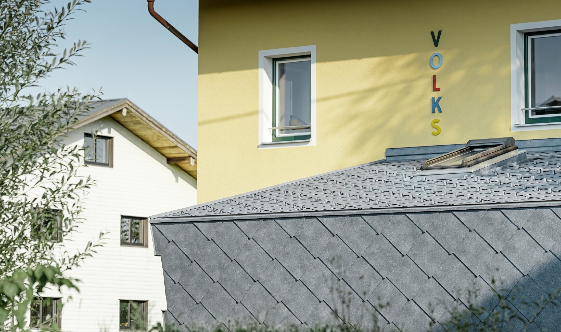 Annexe d’une école primaire — Habillée de losanges de toiture et de façade PREFA en aluminium de couleur gris pierre