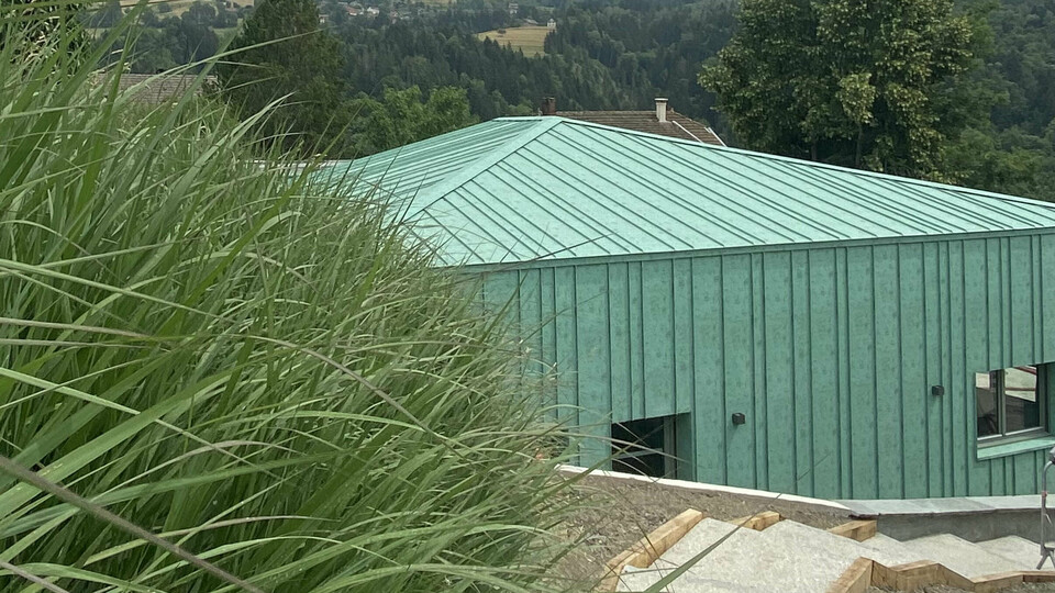 Vue éloignée la nouvelle crèche des Adrets dont la toiture et la façade sont habillées de joint debout Prefalz dans la teinte P.10 vert-de-gris