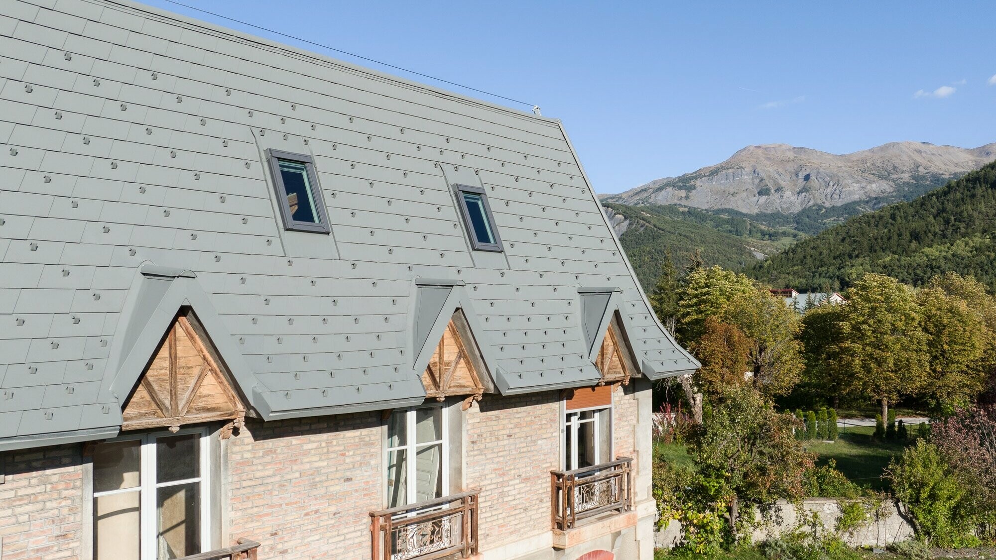 Vue latérale de cette ferme dont la toiture a été rénovée grâce aux bardeaux PREFA dans la teinte P.10 gris souris stucco