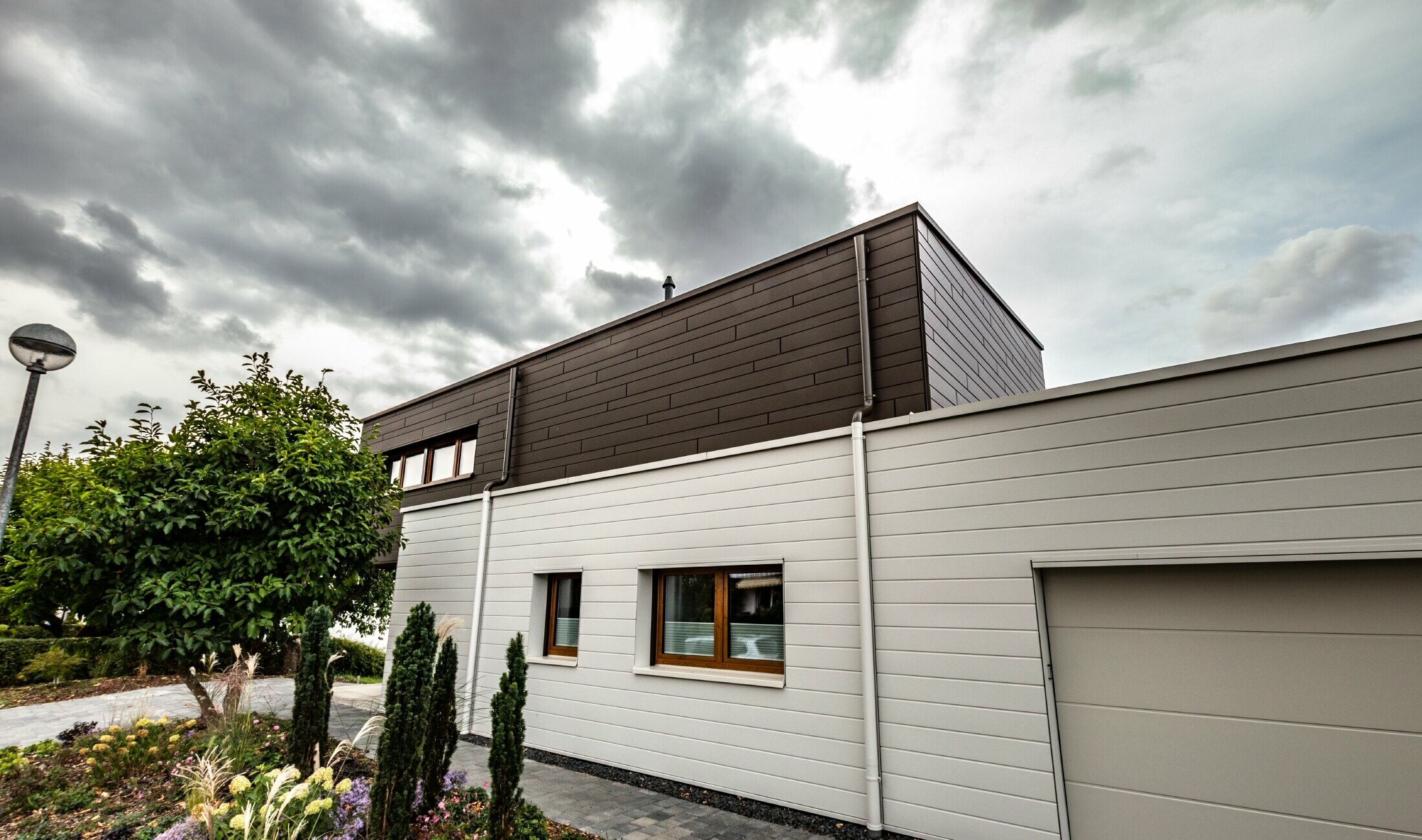 Habillage de façade d’un garage avec les Sidings PREFA à l’horizontale en blanc, avec embranchement d’évacuation.