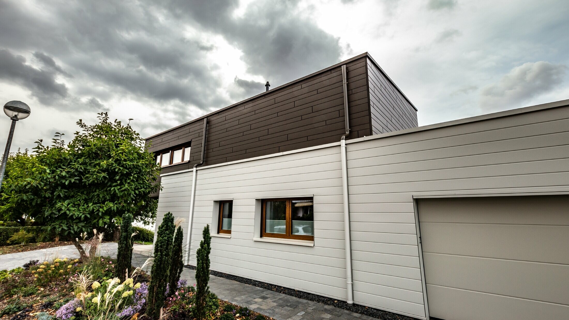 Habillage de façade d’un garage avec les Sidings PREFA à l’horizontale en blanc, avec embranchement d’évacuation.