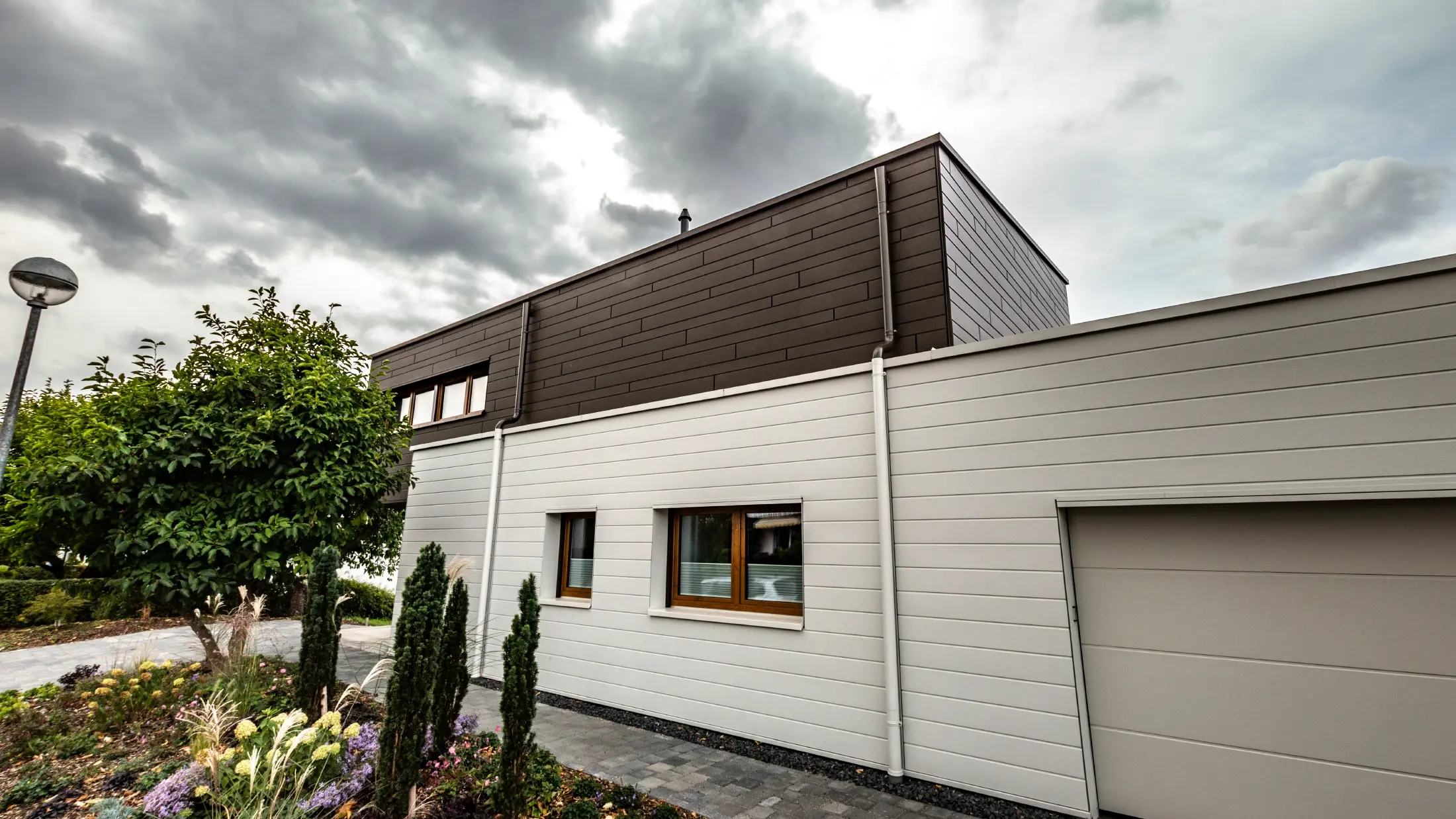 Habillage de façade d’un garage avec les Sidings PREFA à l’horizontale en blanc, avec embranchement d’évacuation.