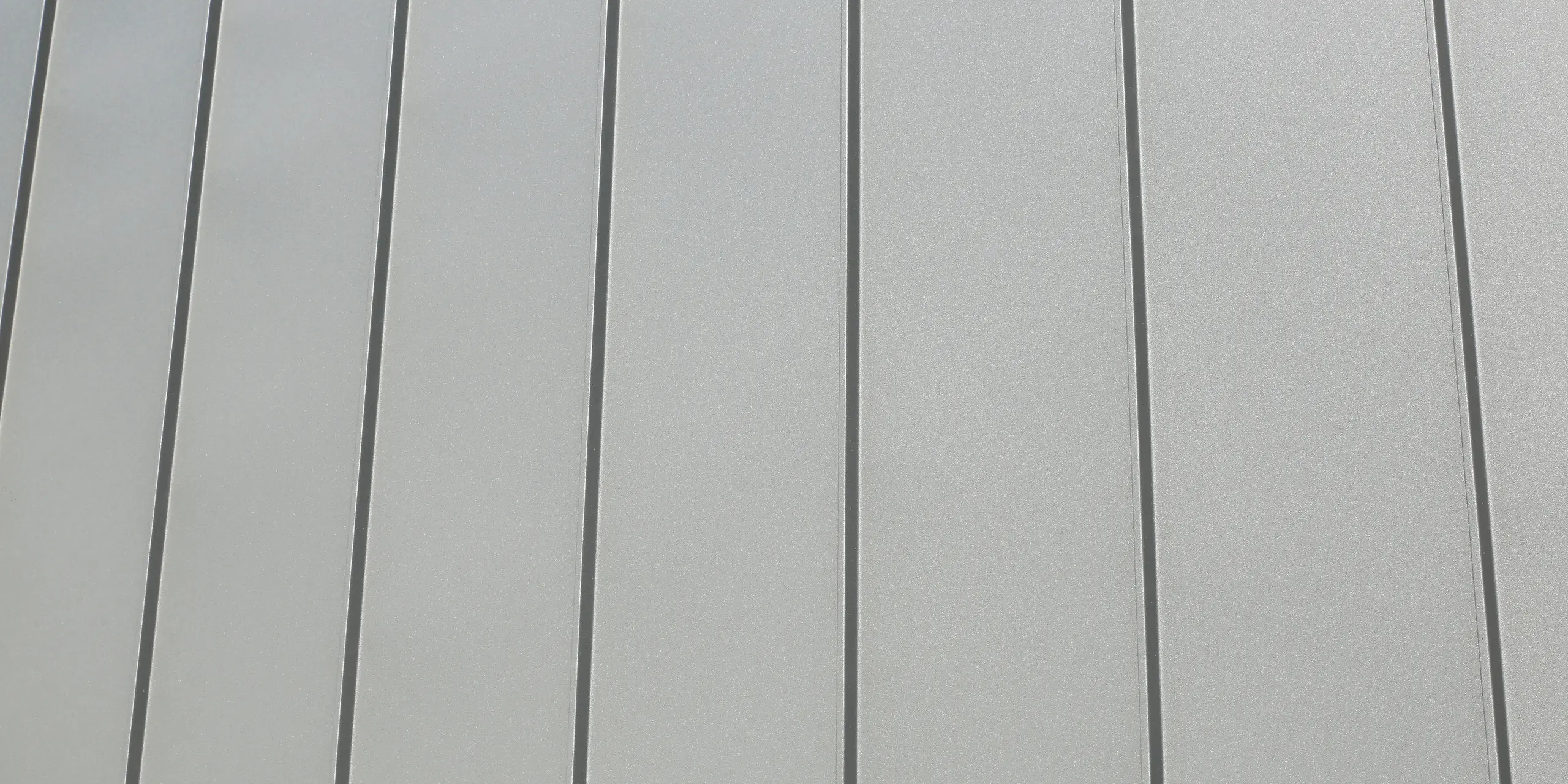 Le joint debout PREFALZ en gris souris s'étend sur les façades et les toits à pignon d'un lotissement mitoyen à Mundolsheim. Les coques uniformes du bâtiment en aluminium créent une image globale harmonieuse.