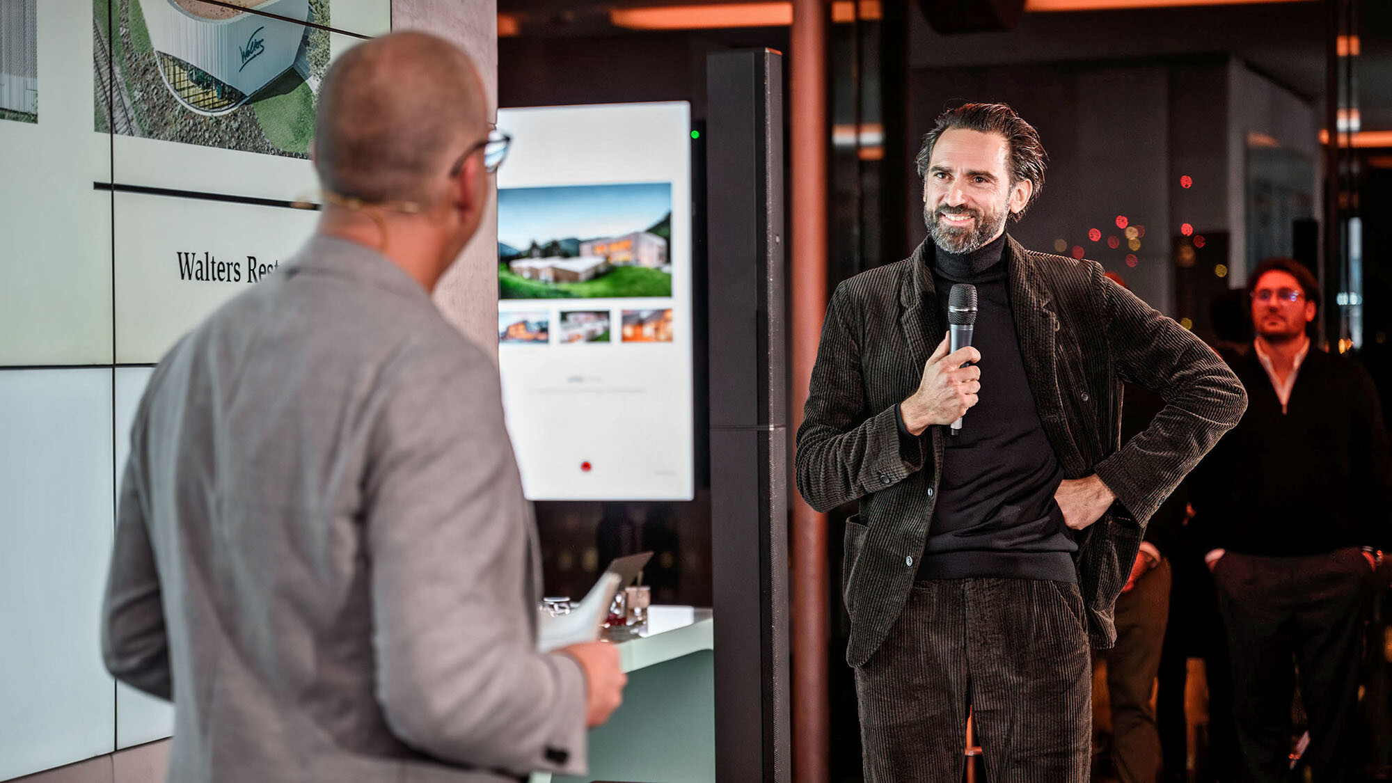 Le directeur marketing international Jürgen Jungmair et l'architecte Thomas Heil du bureau autrichien dreiplus Architekten conversant devant l'espace de présentation.