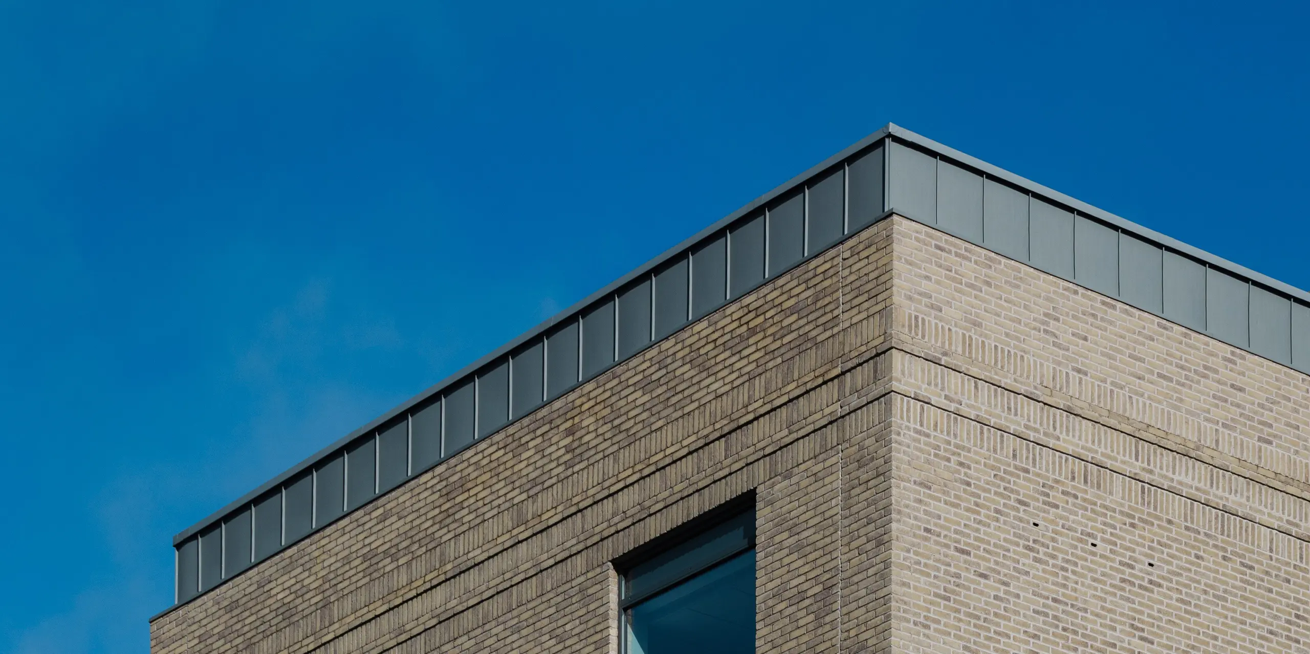 Le Northern Regional College de Ballymena est un bâtiment scolaire remarquable, aux lignes épurées et construit avec des matériaux de grande qualité. Sa façade en briques claires est coiffée de bacs verticaux en aluminium PREFALZ à joints debout, de couleur gris patiné, qui attirent le regard. L'aluminium PREFA, d'une grande durabilité, séduit par sa résistance aux intempéries, sa légèreté et son élégance. Sa teinte grise apaisante crée un contraste saisissant avec les surfaces vitrées et le ciel, conférant au bâtiment une présence architecturale intemporelle.