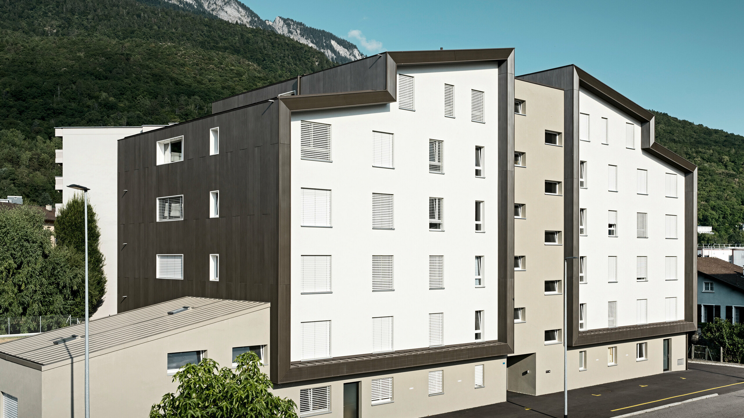 La façade du complexe résidentiel Les Dailles a été largement recouverte de l'impressionnant profil triangle PREFA en bronze. Le toit du bâtiment a été recouvert de PREFALZ en bronze.