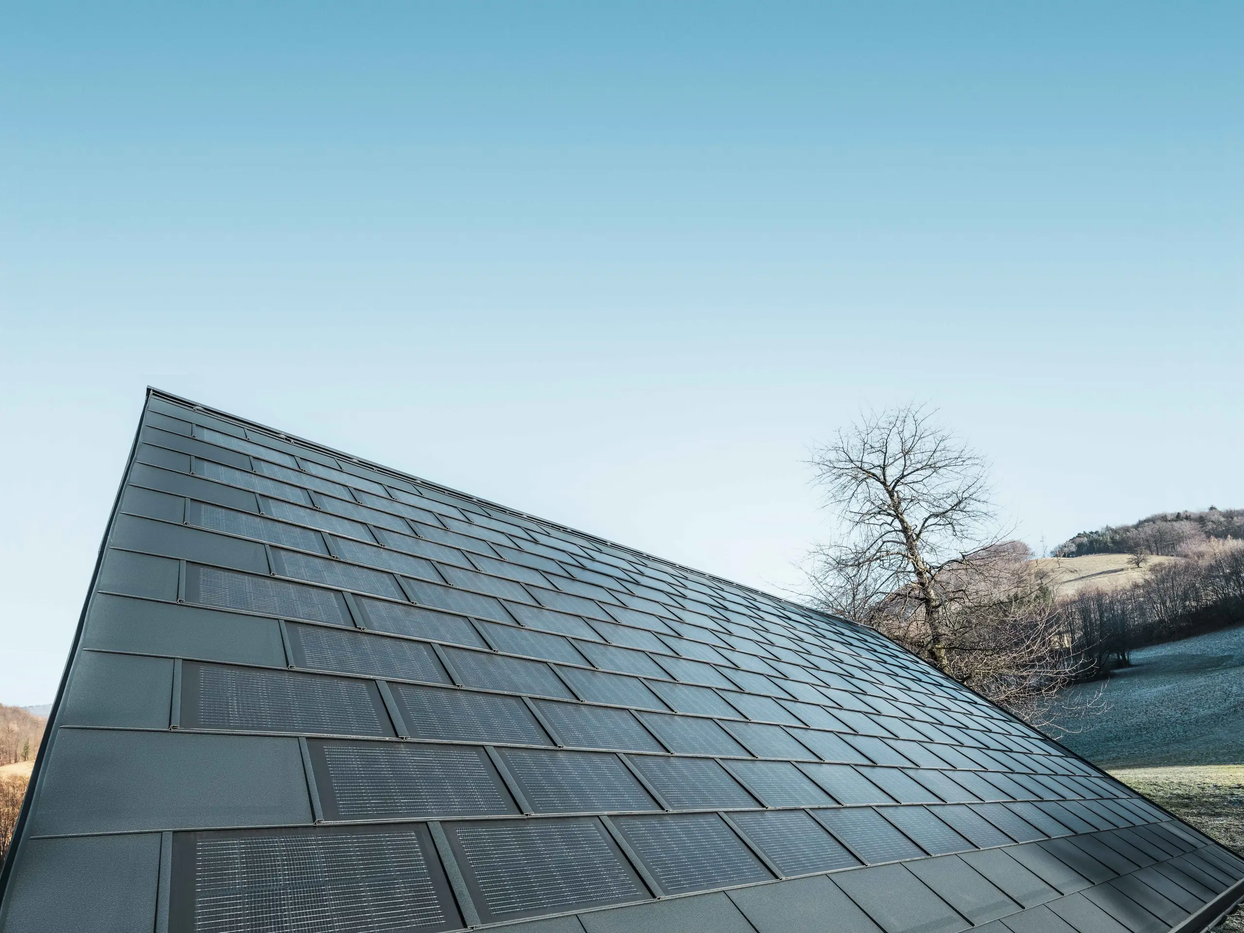 Photo d'une surface recouverte de tuiles solaires couleur anthracite, combinées au R.16