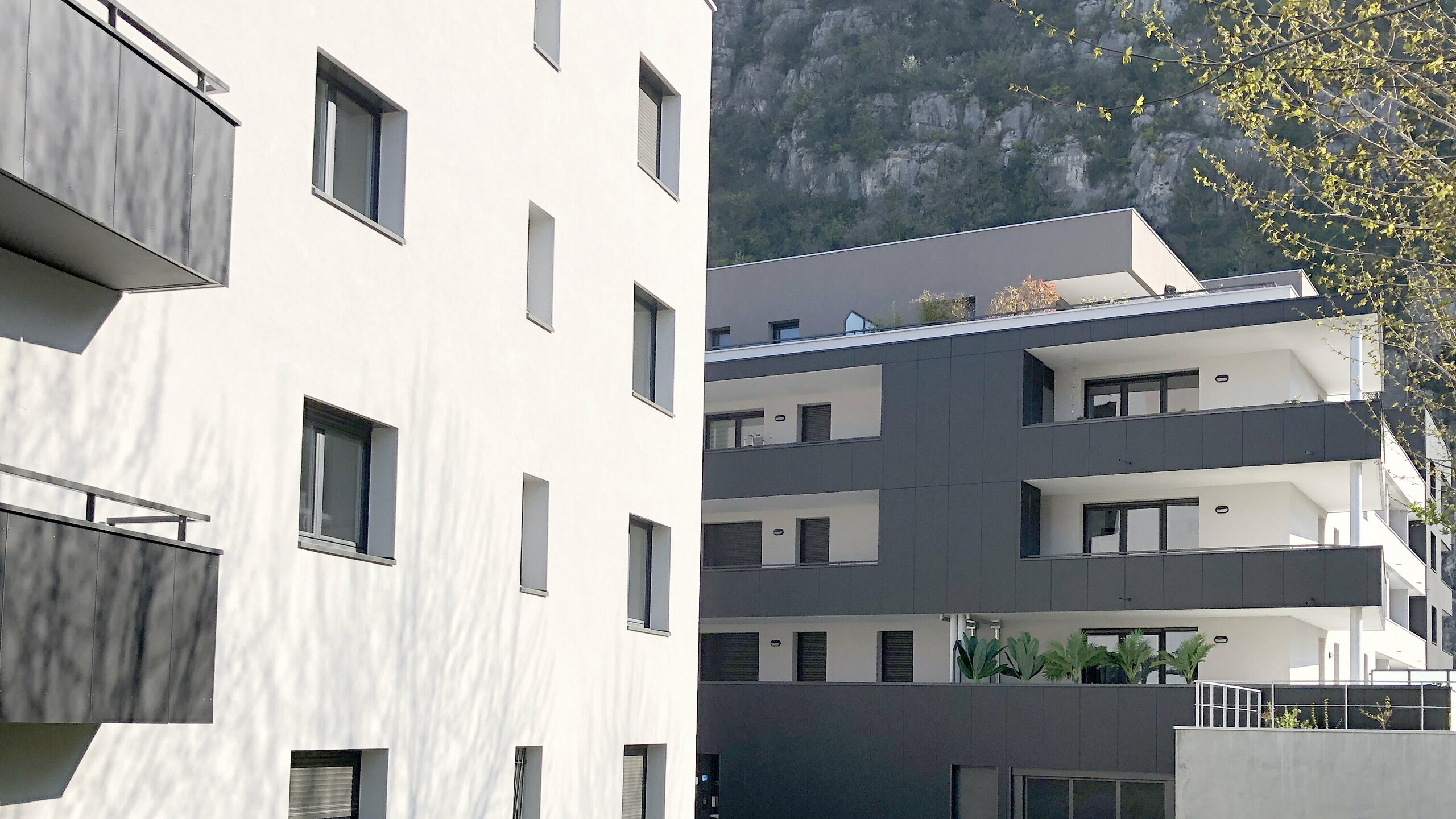Vue d'ensemble de la résidence Ambre & Onyx recouverte de panneaux composites en aluminium PREFABOND dans la teinte gris noir. Le deuxième bâtiment est en crépis. 